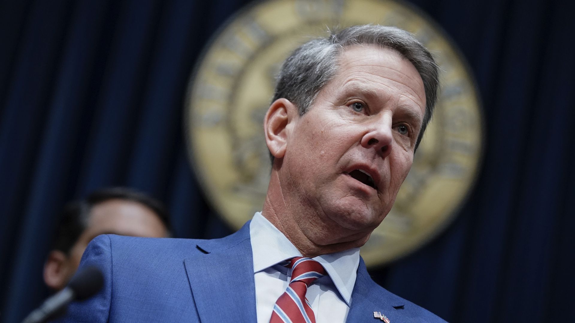A close-up of Governor Brian Kemp talking to reporters