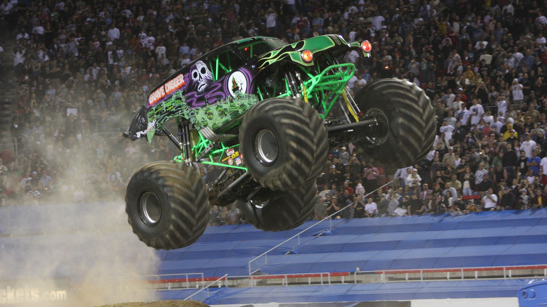 Photo shows a monster truck airborne while at a Monster Jam track