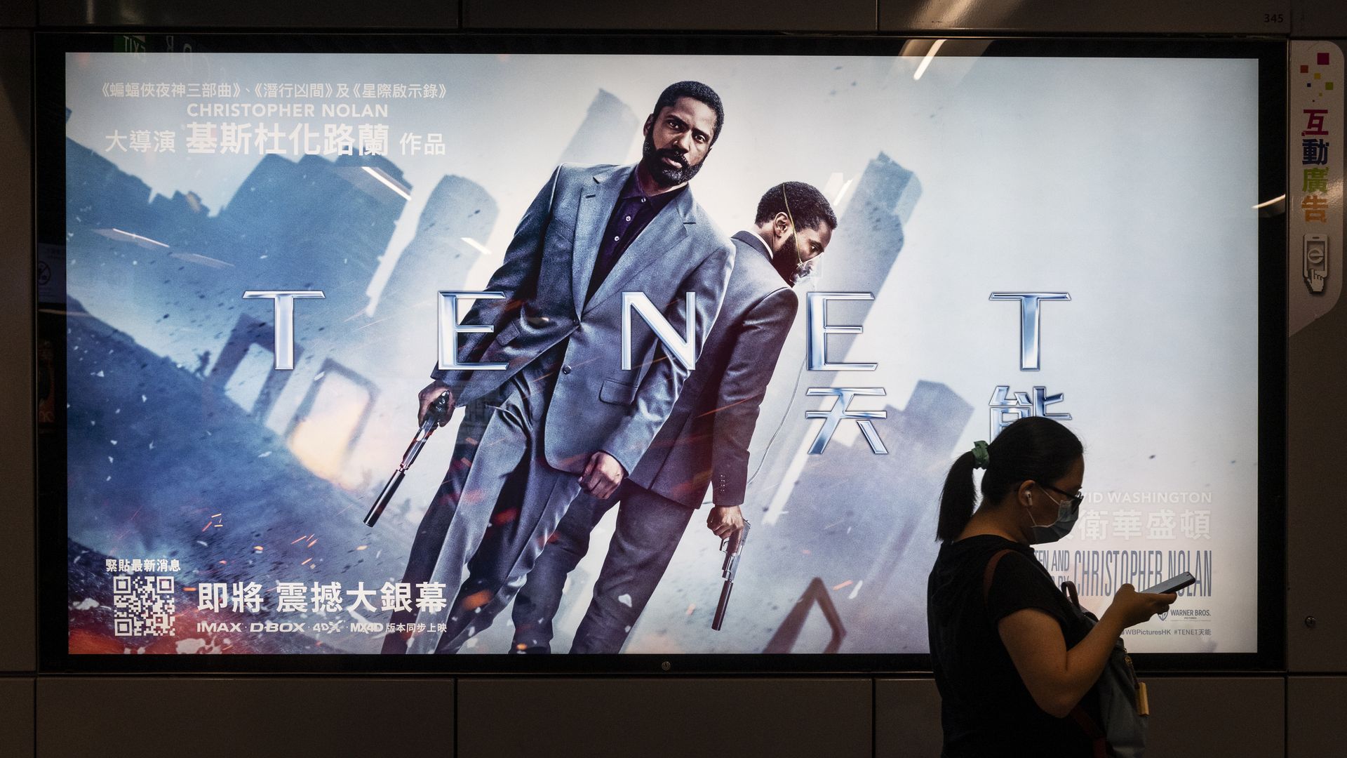 A commuter walks by a sign promoting the film "Tenet"