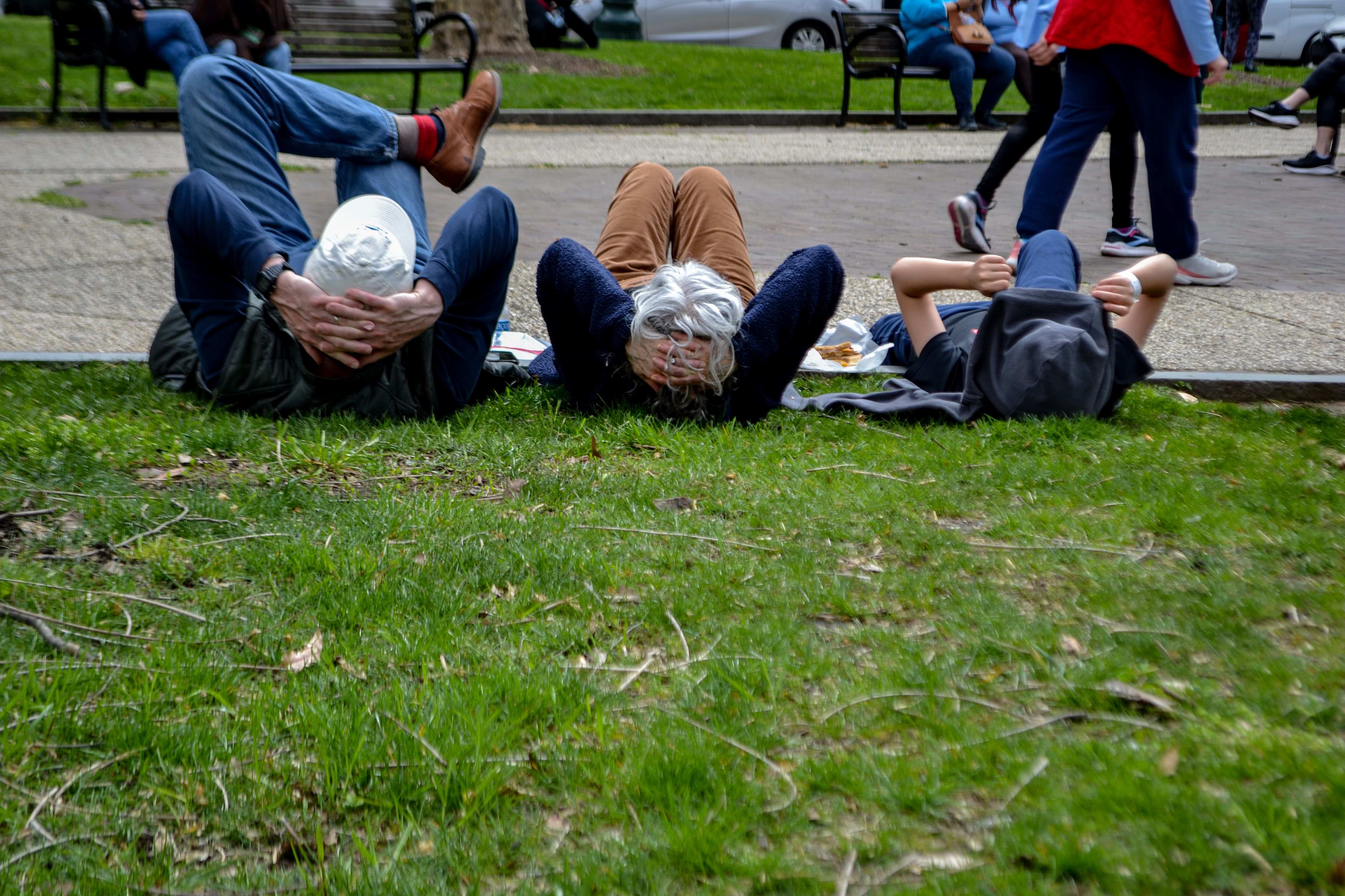 Three people lying down on the grass.