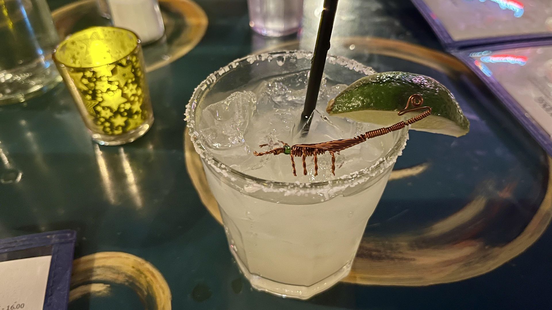 A margarita glass with a metal scorpion in the drink.