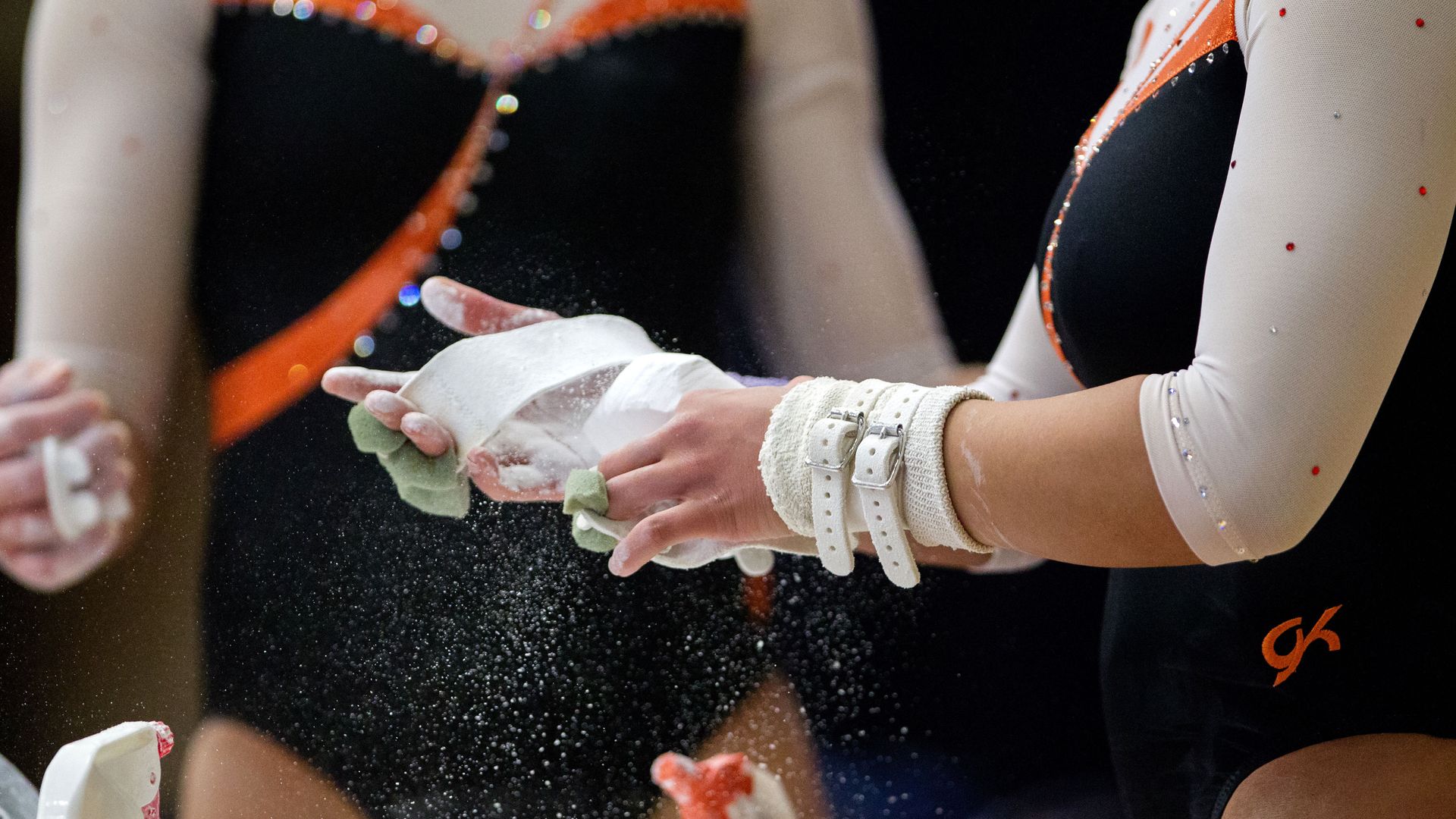 Gymnasts chalk their hands.