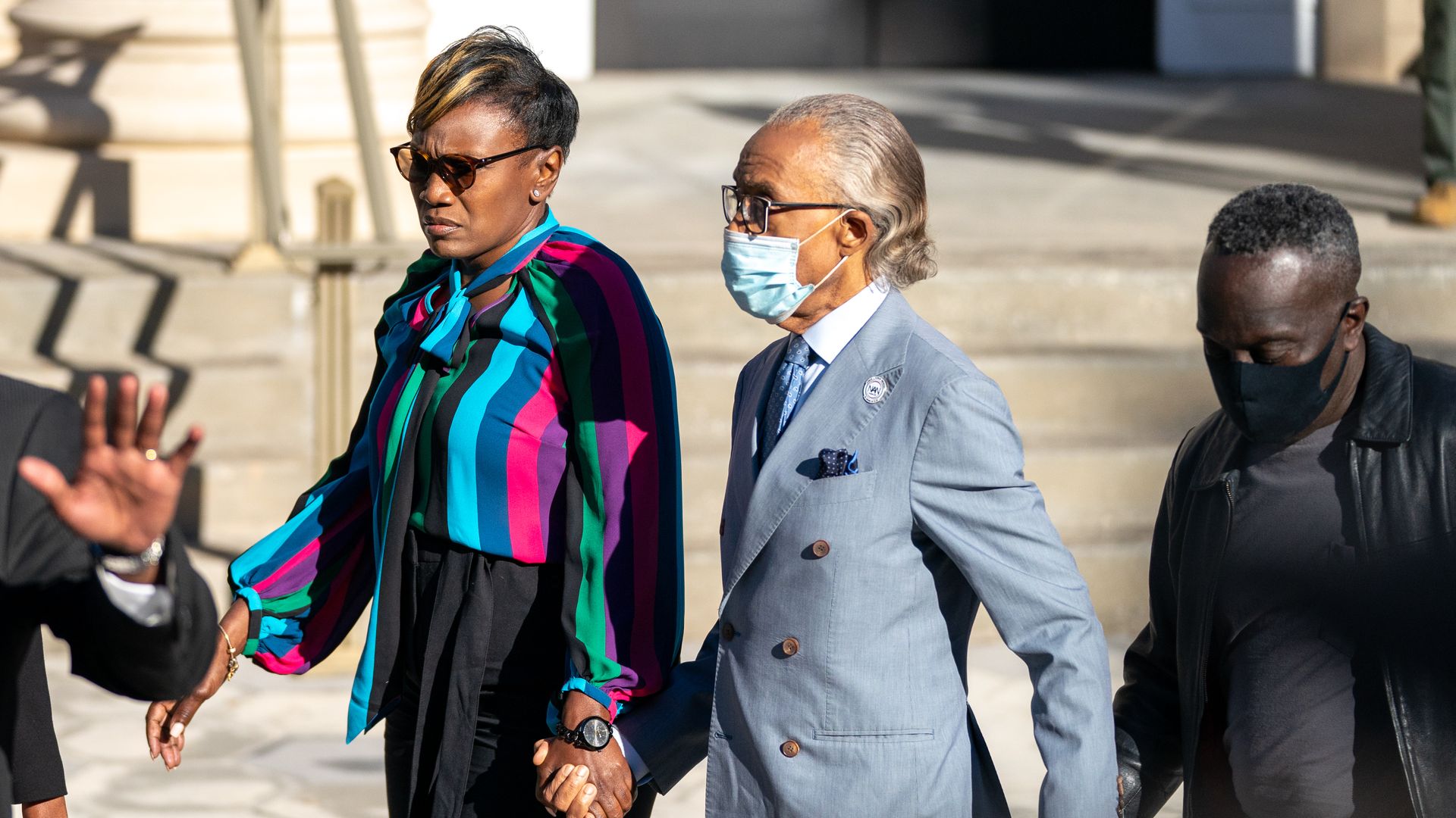 Picture of Ahmaud Arbery's parents holding hands with Rev. Al Sharpton