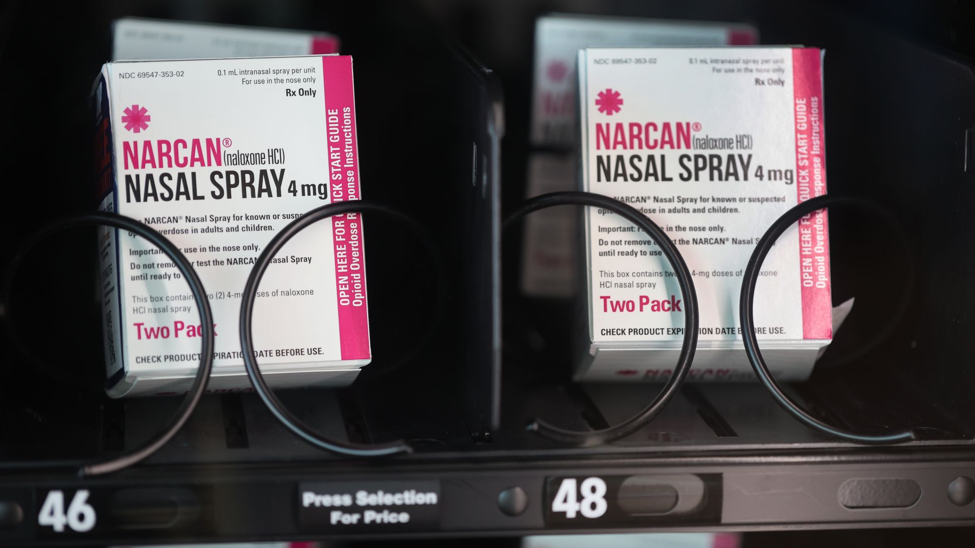 Two pink and white boxes of Narcan nasal spray next to each other in a vending machine
