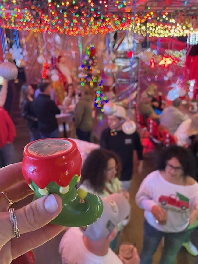 hand holding a shot glass in the shape of a holiday stocking