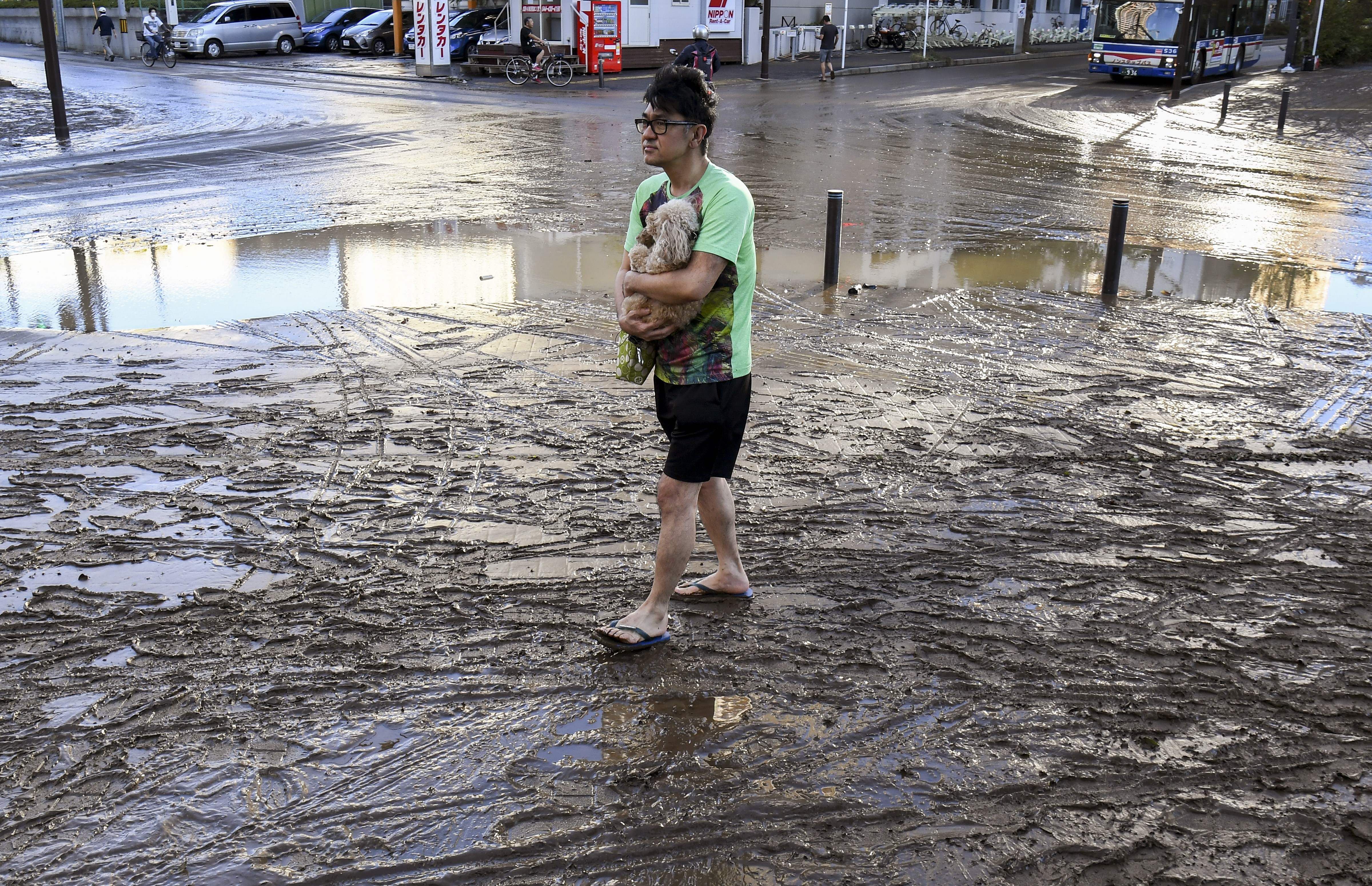A man carries his dog through the mud in the aftermath of Typhoon Hagibis, in Kawasaki 