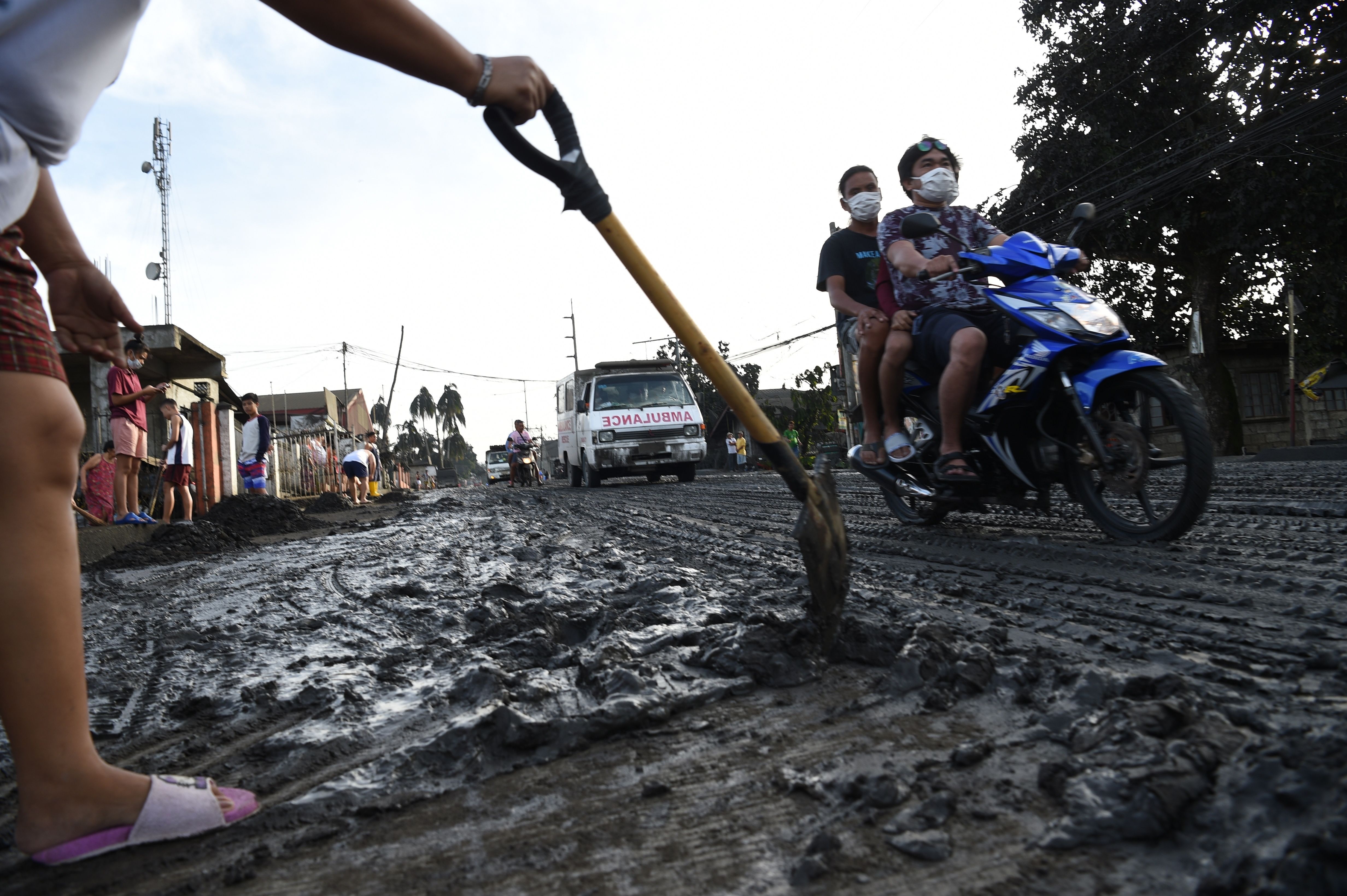 A resident uses a shovel to clear mud and ash spewed by Taal volcano at a development in Tanauan town, Batangas province south of Manila on January 13, 2020.