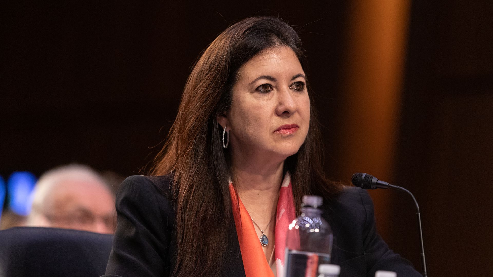 Fed governor Adriana Kugler sitting at a table with water bottles and a microphone in front of her at Kugler's confirmation hearing.