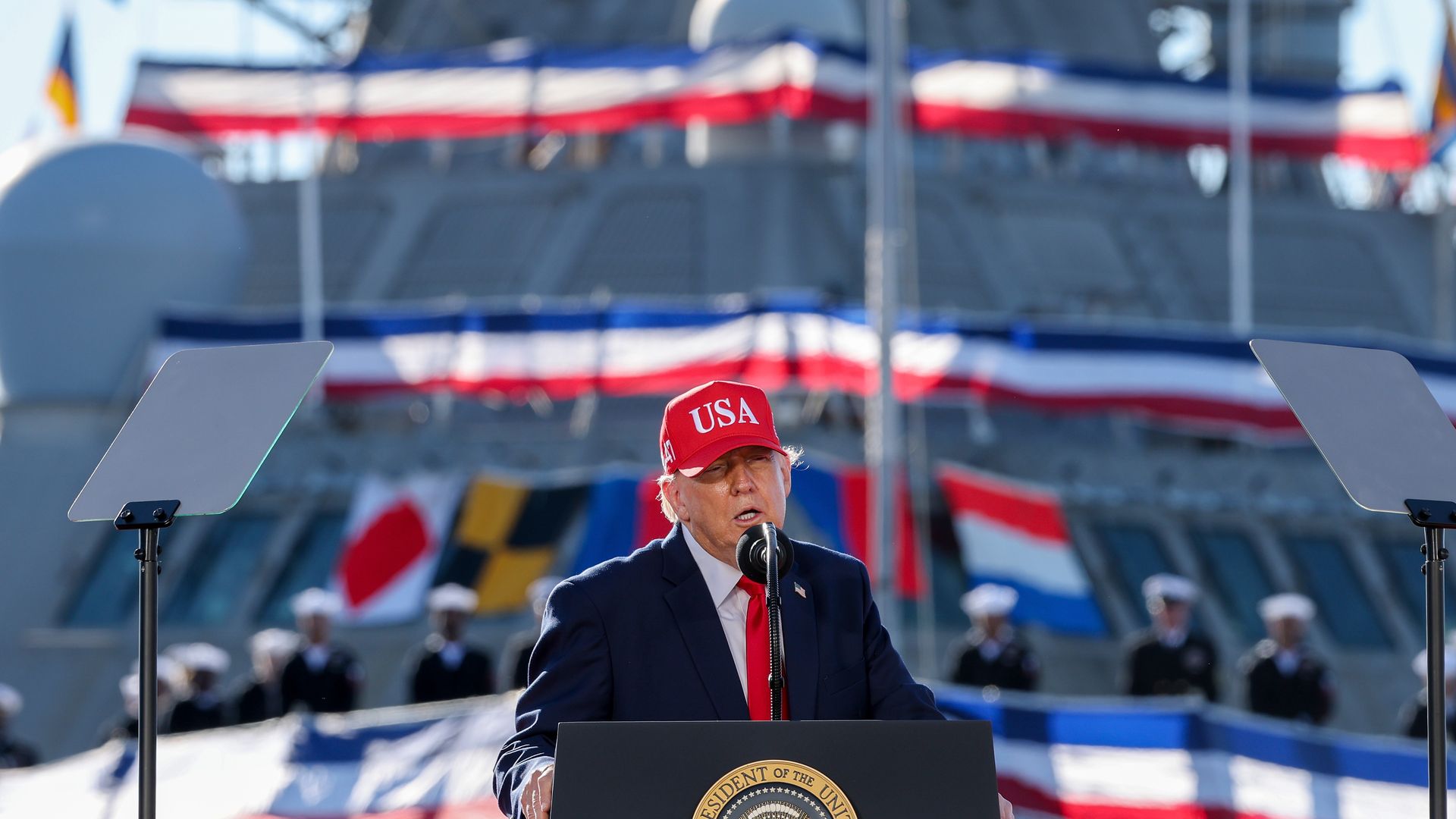 President Trump, wearing a red USA hat, delivers remarks on stage at Tradepoint Atlantic on Tuesday in Sparrows Point, Maryland. 