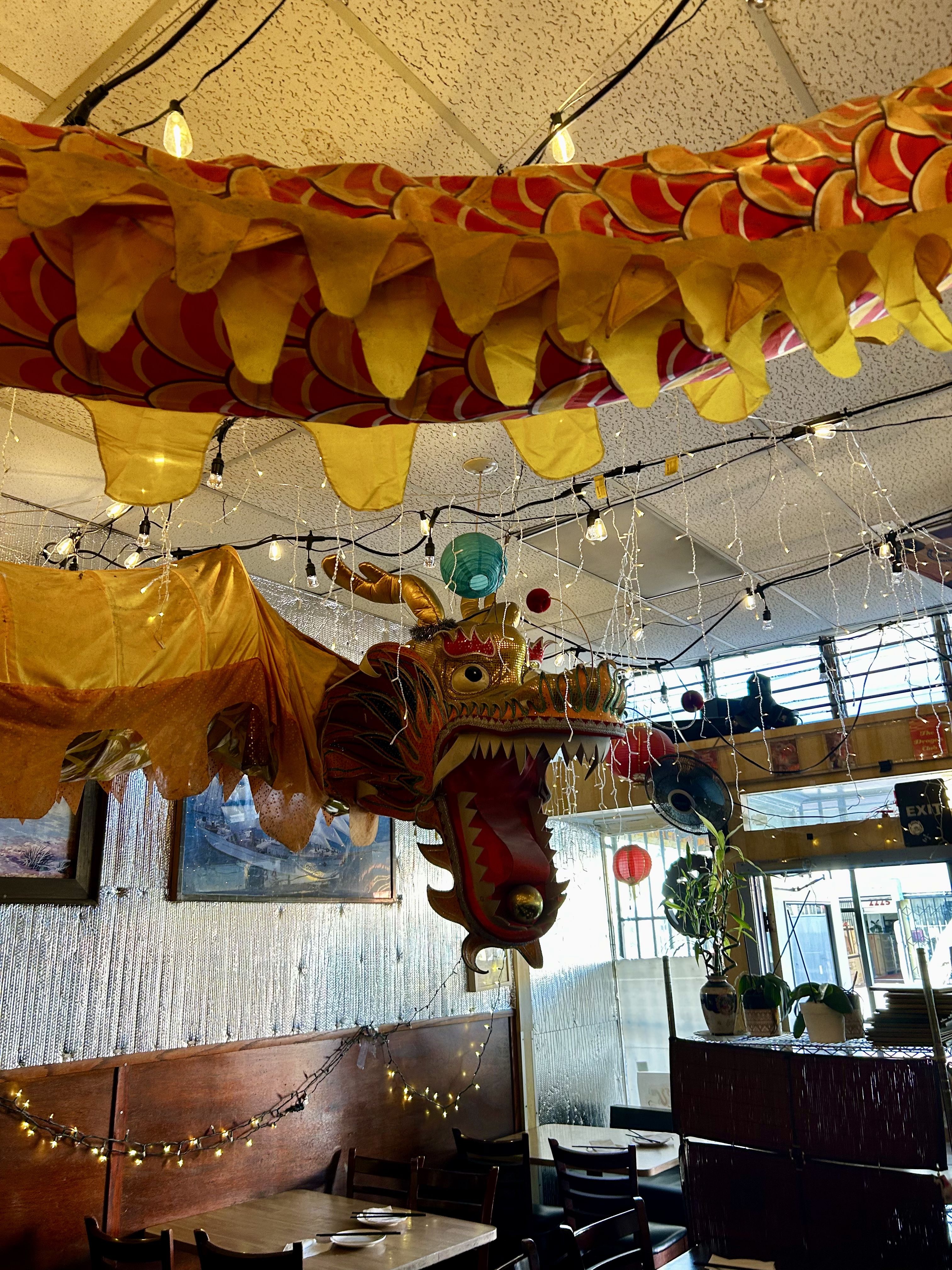Photo of a yellow and red dragon hanging from the ceiling at a restaurant
