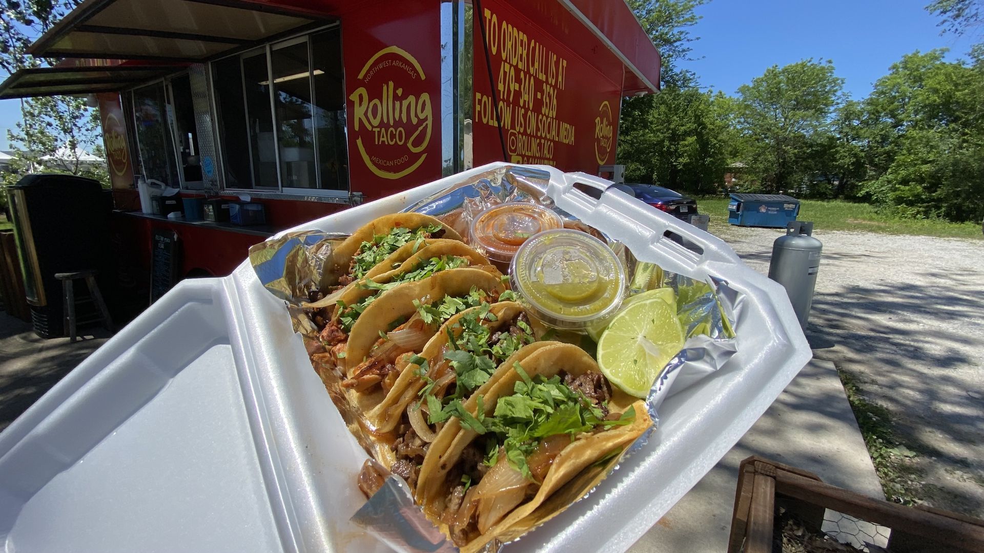 A photo of five street tacos on a take-out plate. 