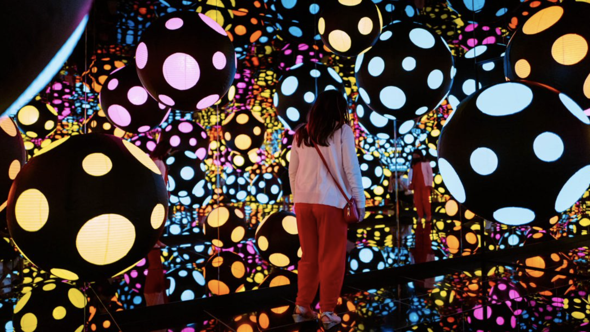 Visitor experiencing Yayoi Kusama’s Infinity Mirrored Room—My Heart Is Dancing into the Universe (2018).