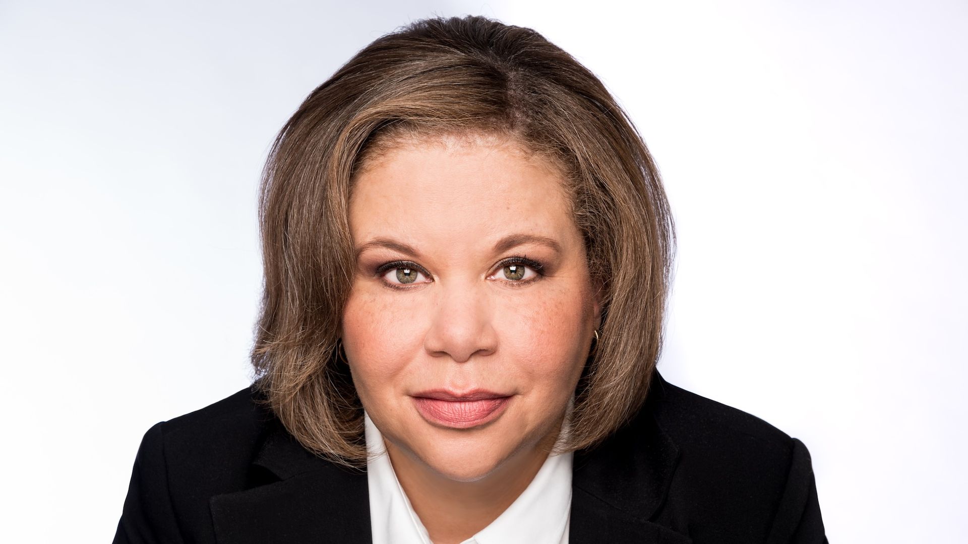 Tracy Clark staring straight on to the camera, wearing a black blazer and white shirt.