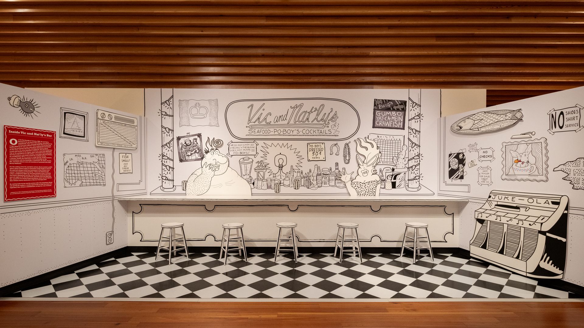 A retro diner mural along the back wall featuring "Vic and Nat's" sign, cartoon drawings, and five white bar stools in front of a black-and-white checkered floor and wooden slat ceiling.