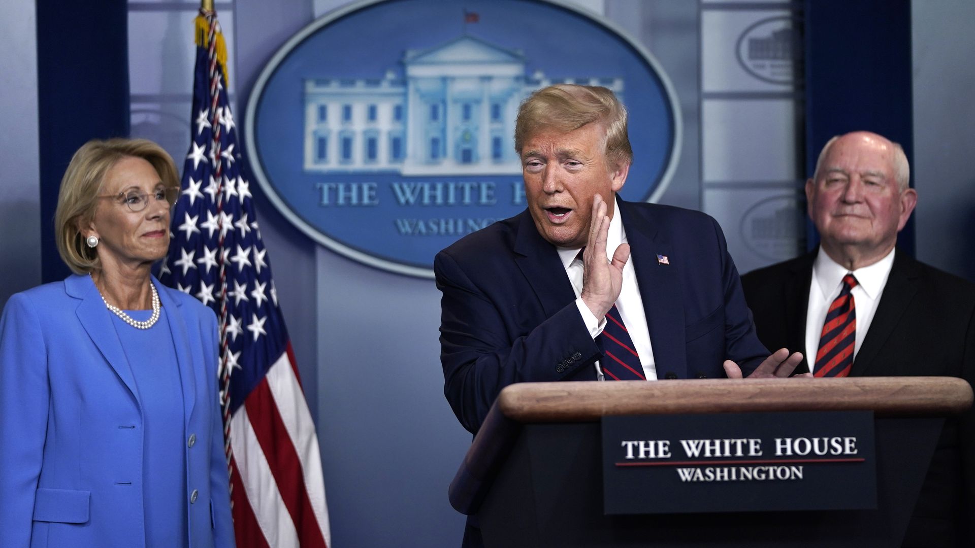 In this image, Trump and Besty DeVos brief reporters at the White House