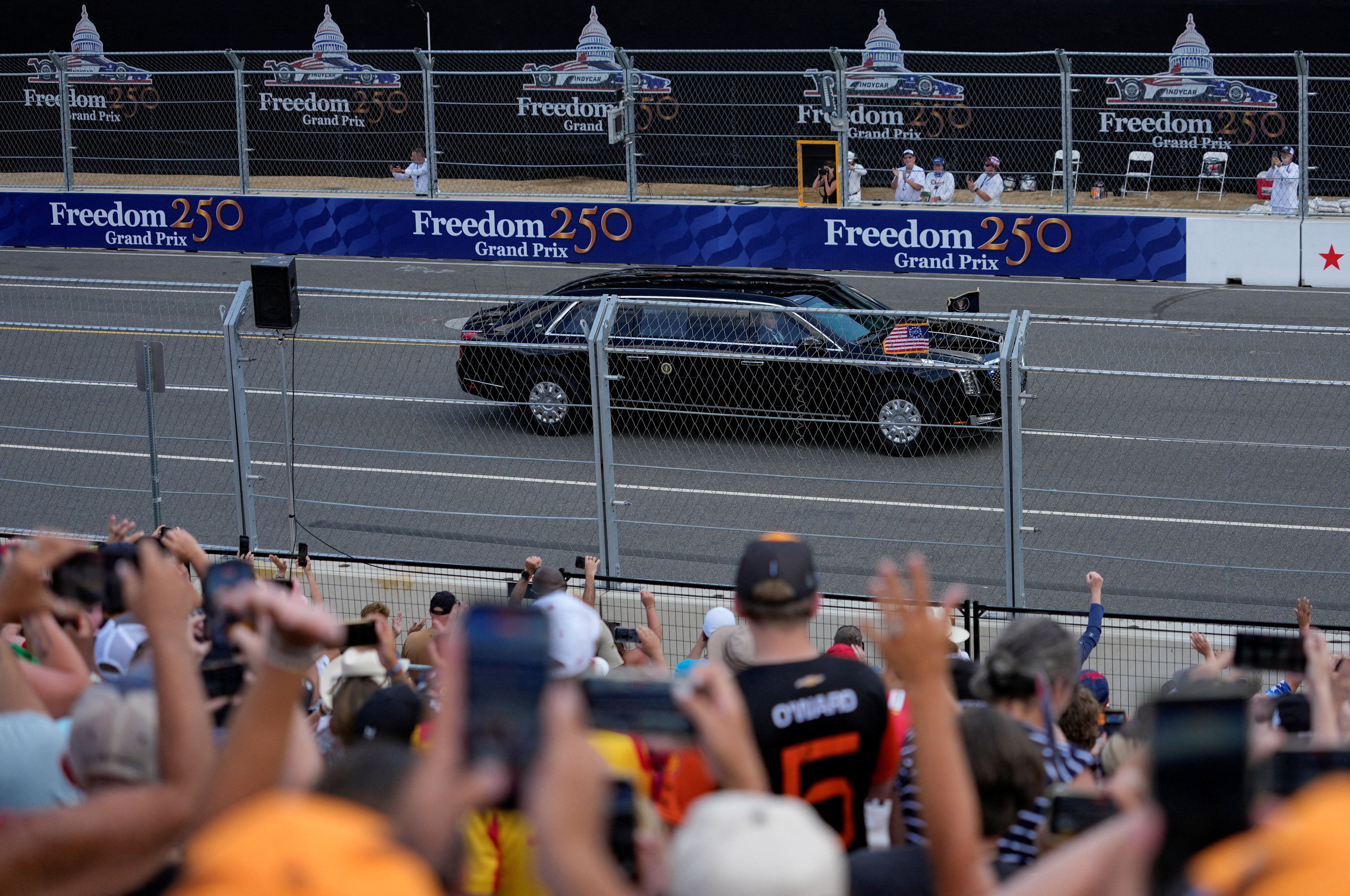 A black limousine drives along the track as spectators watch