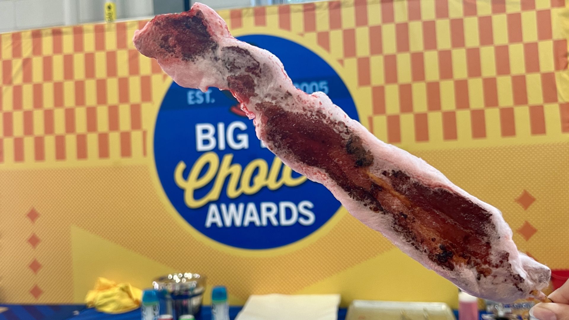 Fried bacon on a stick, surrounded by cotton candy