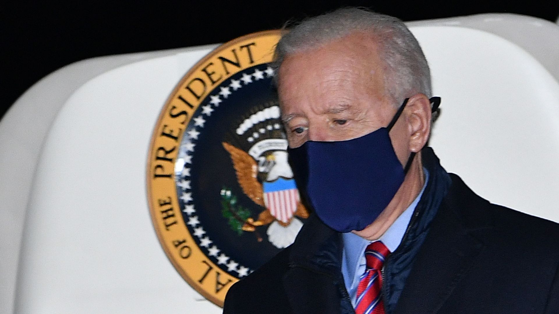 Joe Biden stands in front of a presidential seal 