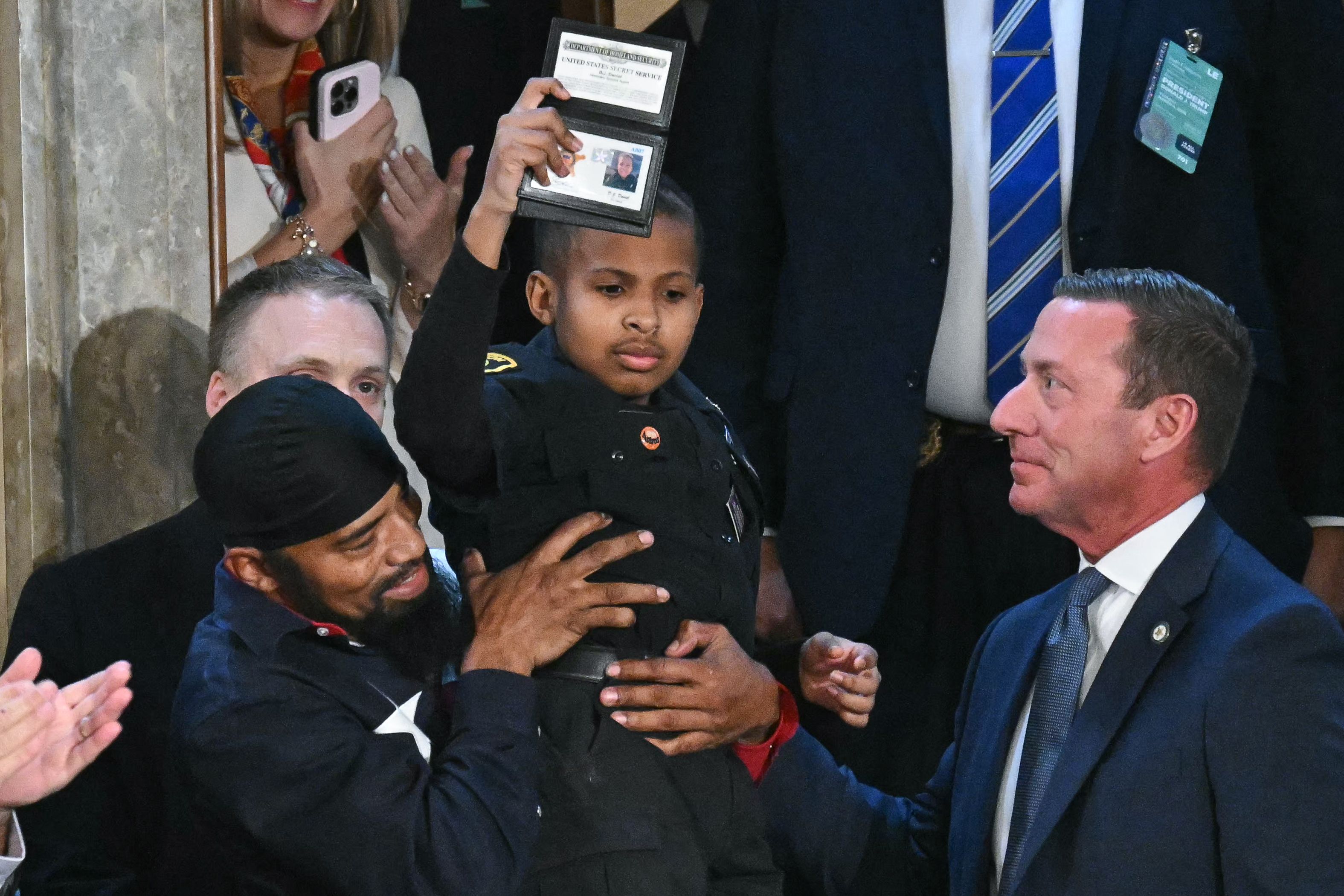 3-year-old cancer survivor Devarjaye "DJ" Daniel is lifted up by his father Theodis Daniel after given credentials from US Secret Service Director Sean Curran after US President Donald Trump made him an honorary member of the US Secret Service during his address to a joint session of Congress at the