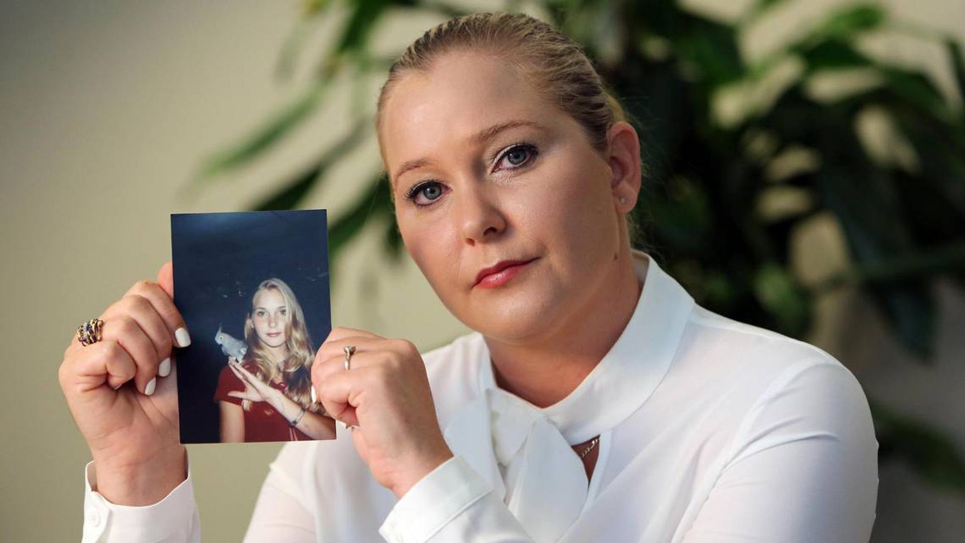 Virginia Giuffre holding a photo of her younger self