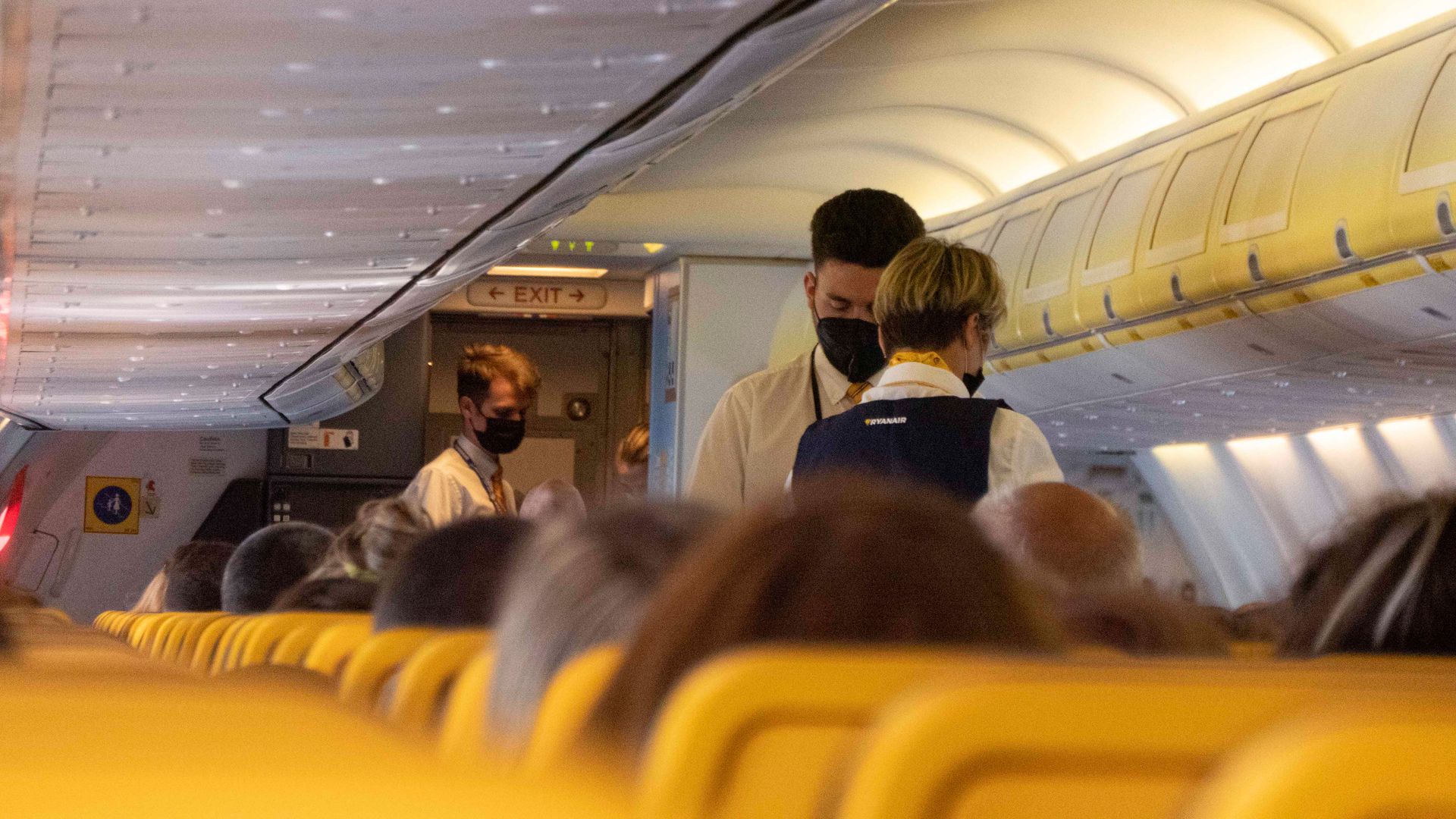 Photo of flight attendants tending to passengers aboard an airplane