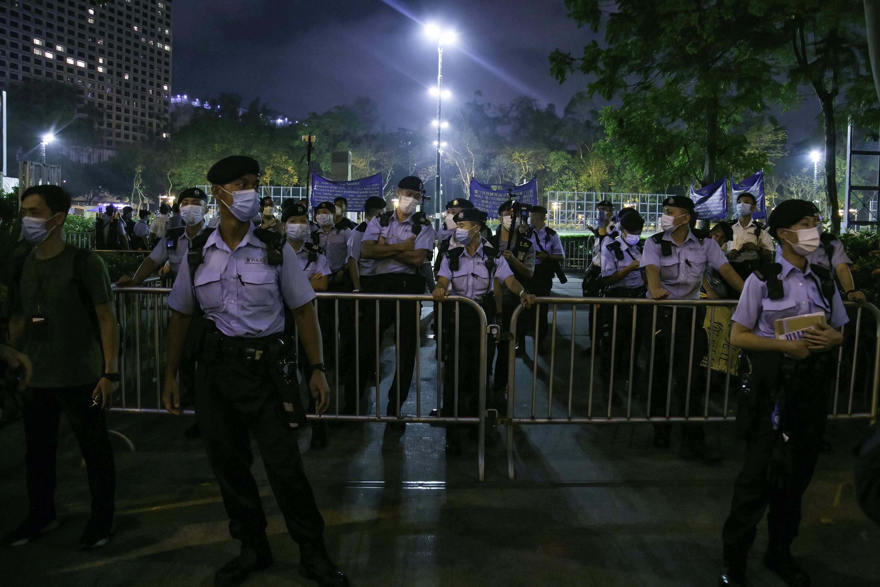 Photo of a crowd of police officers standing at the entrance of a park under the night sky