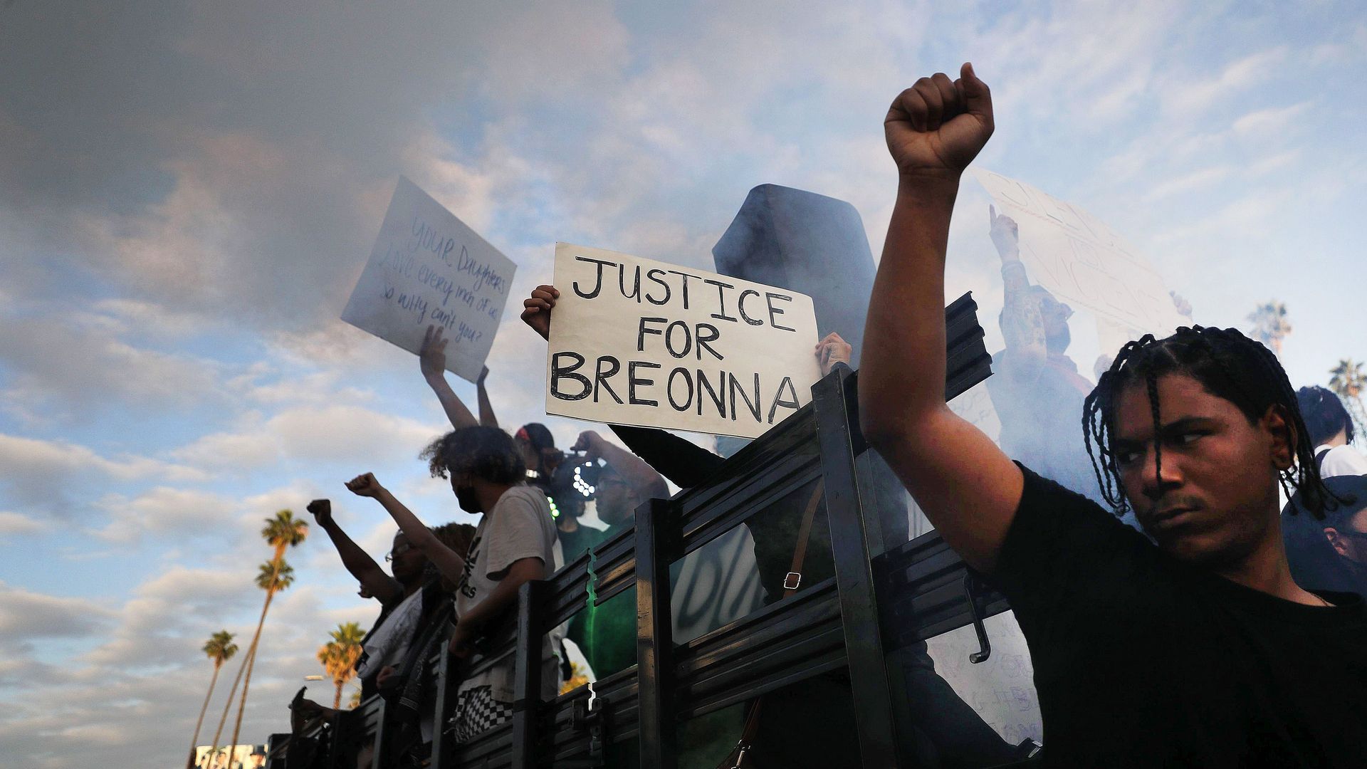 Protesters ride aboard a vehicle with a smoke machine, with a sign reading 'Justice for Breonna', during a peaceful demonstration