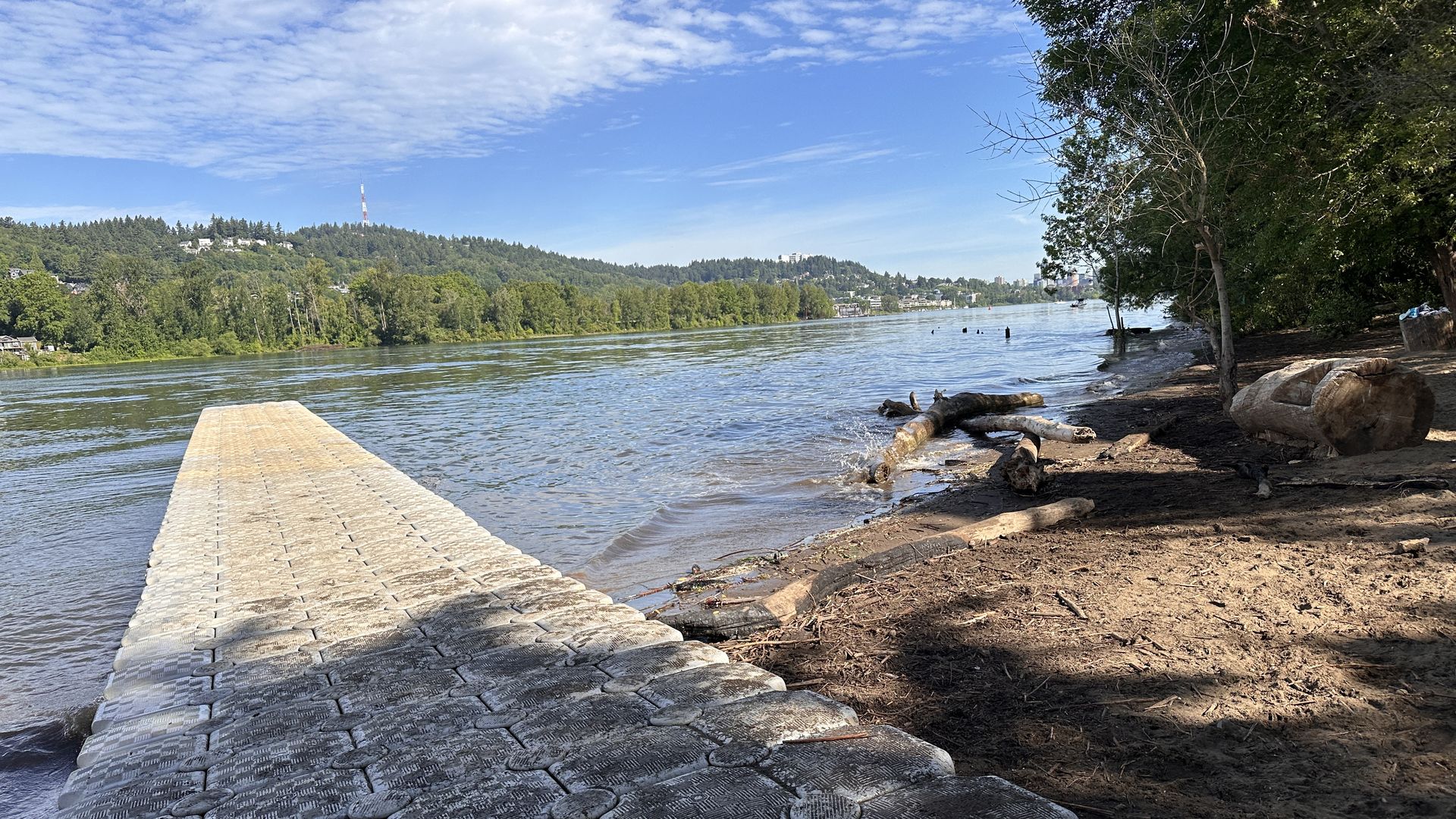 White plastic dock in a river with trees on the other shore 