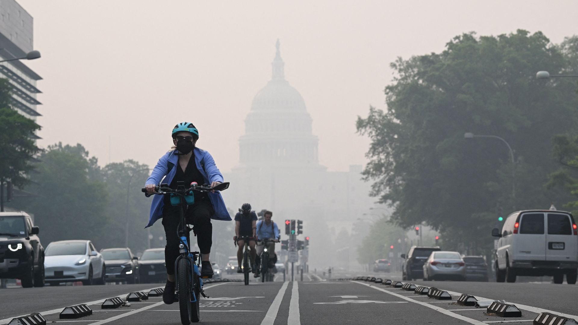 A person riding a bike down Independence Avenue with a blanket of smoke partially obscuring the U.S. Capitol in Washington, D.C., on June 8.