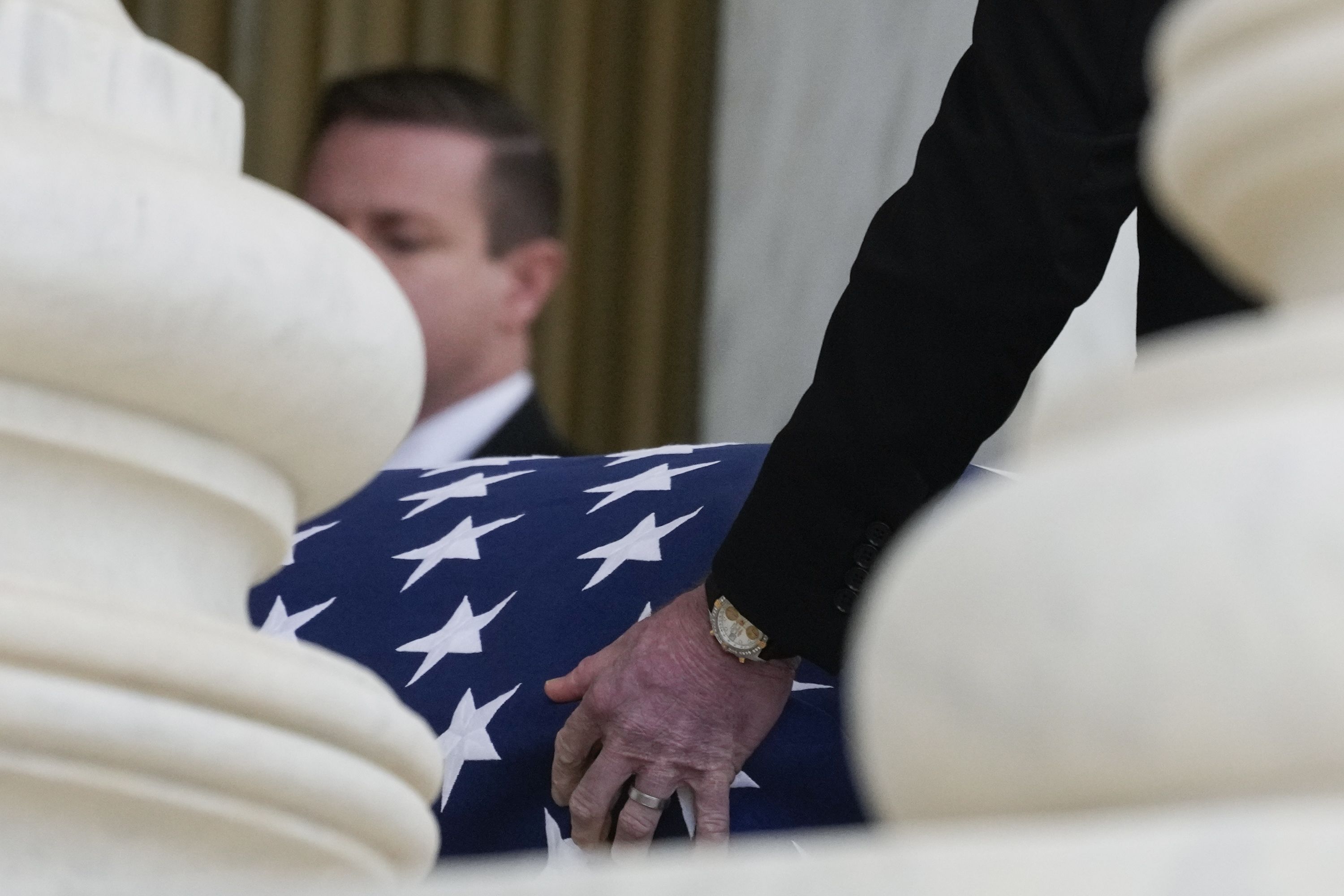 An image of a hand touching the flag of the casket.