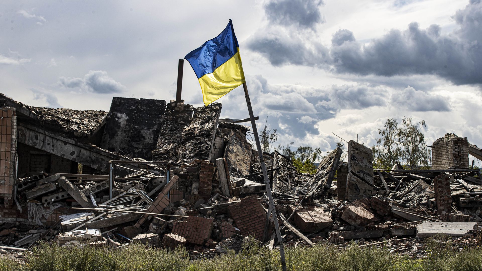 krainian flag waves in a residential area heavily damaged in the village of Dolyna in Donetsk Oblast,