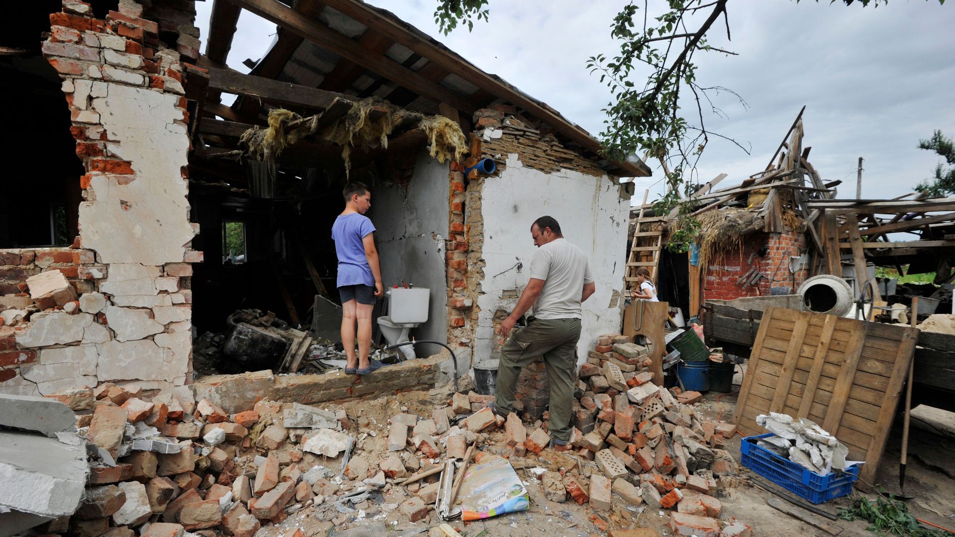 People clear debris of a house
