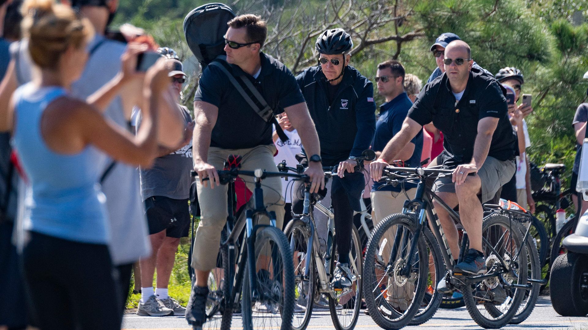 President Biden is seen taking a bike ride flanked by Secret Service agents.