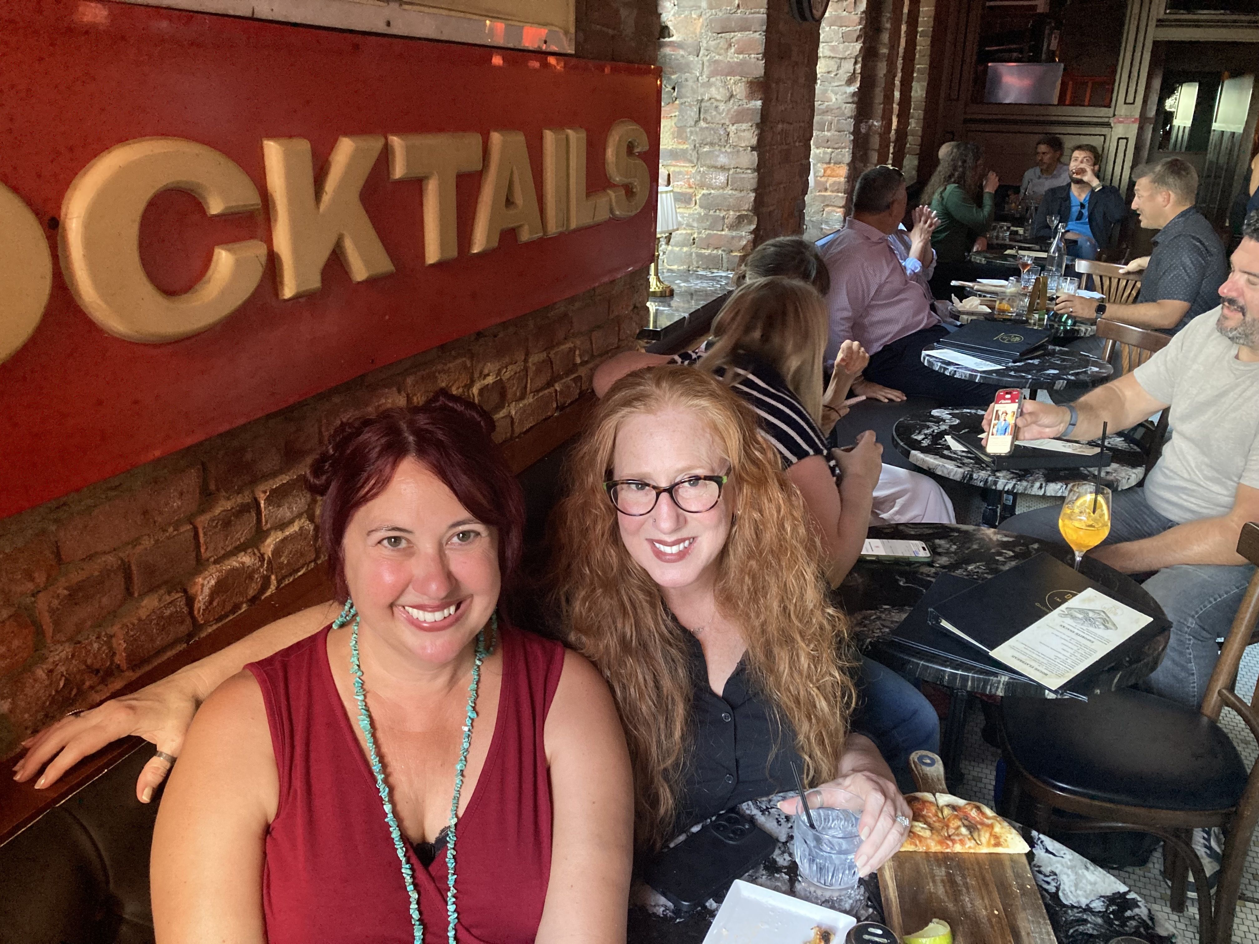 Two women in a bar, smiling and looking at the camera.