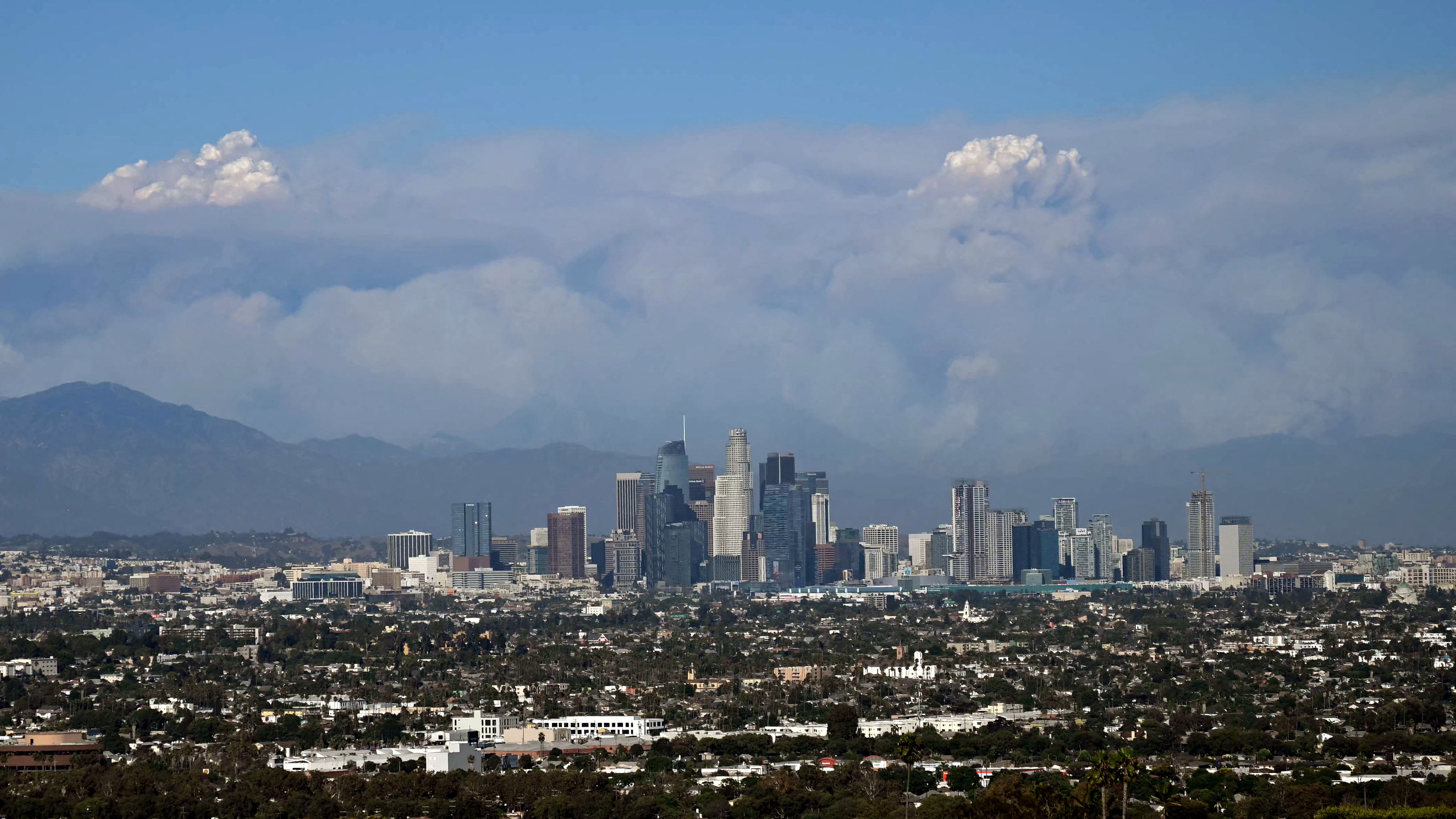 Plumes of smoke rise from wildfires in San Bernardino County mountains, including the Bridge Fire, as seen from Kenneth Hahn Park in Baldwin Hills, Los Angeles