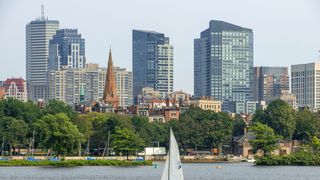 Sail boat in Boston Harbor, Boston against the cityscape of Back Bay Boston, Massachusetts, USA from across the Charles River. 