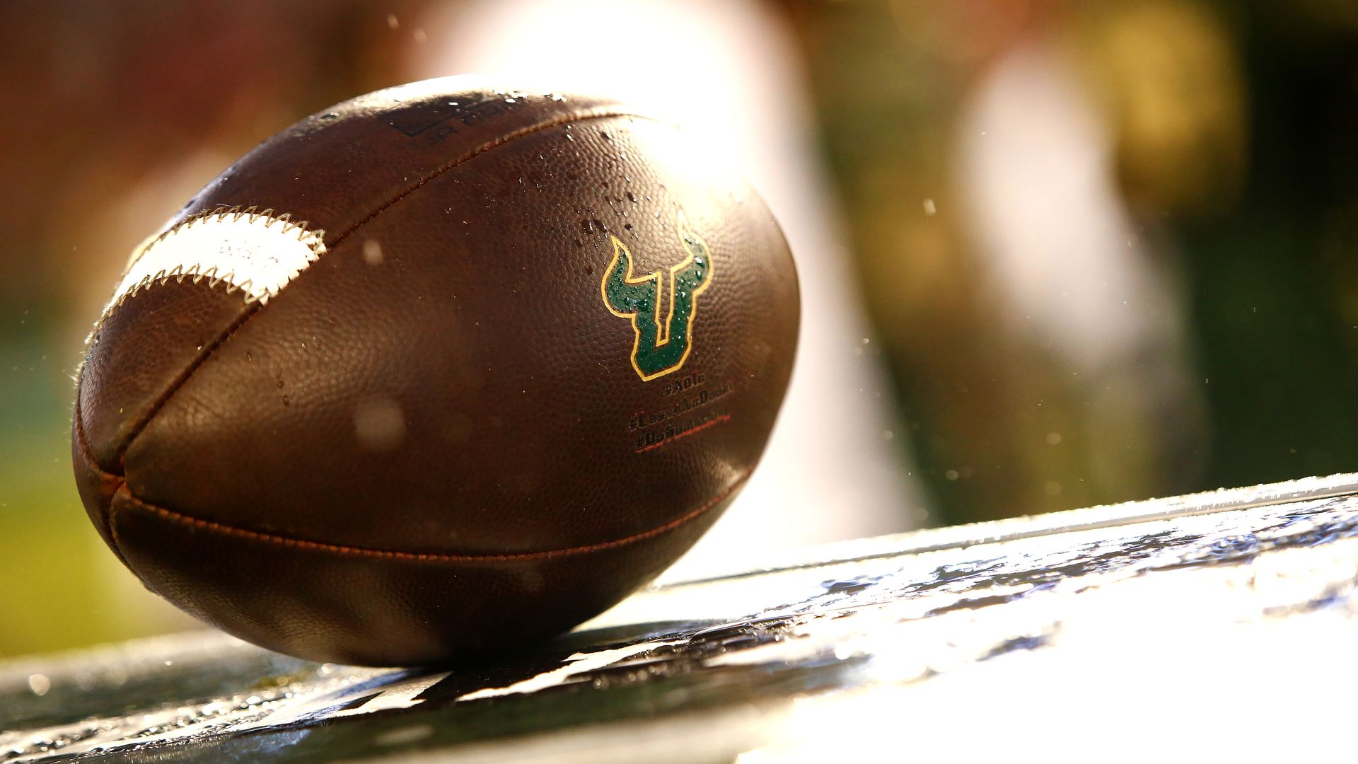 A football adorned with the South Florida Bulls logo sits on a crate on the sidelines.