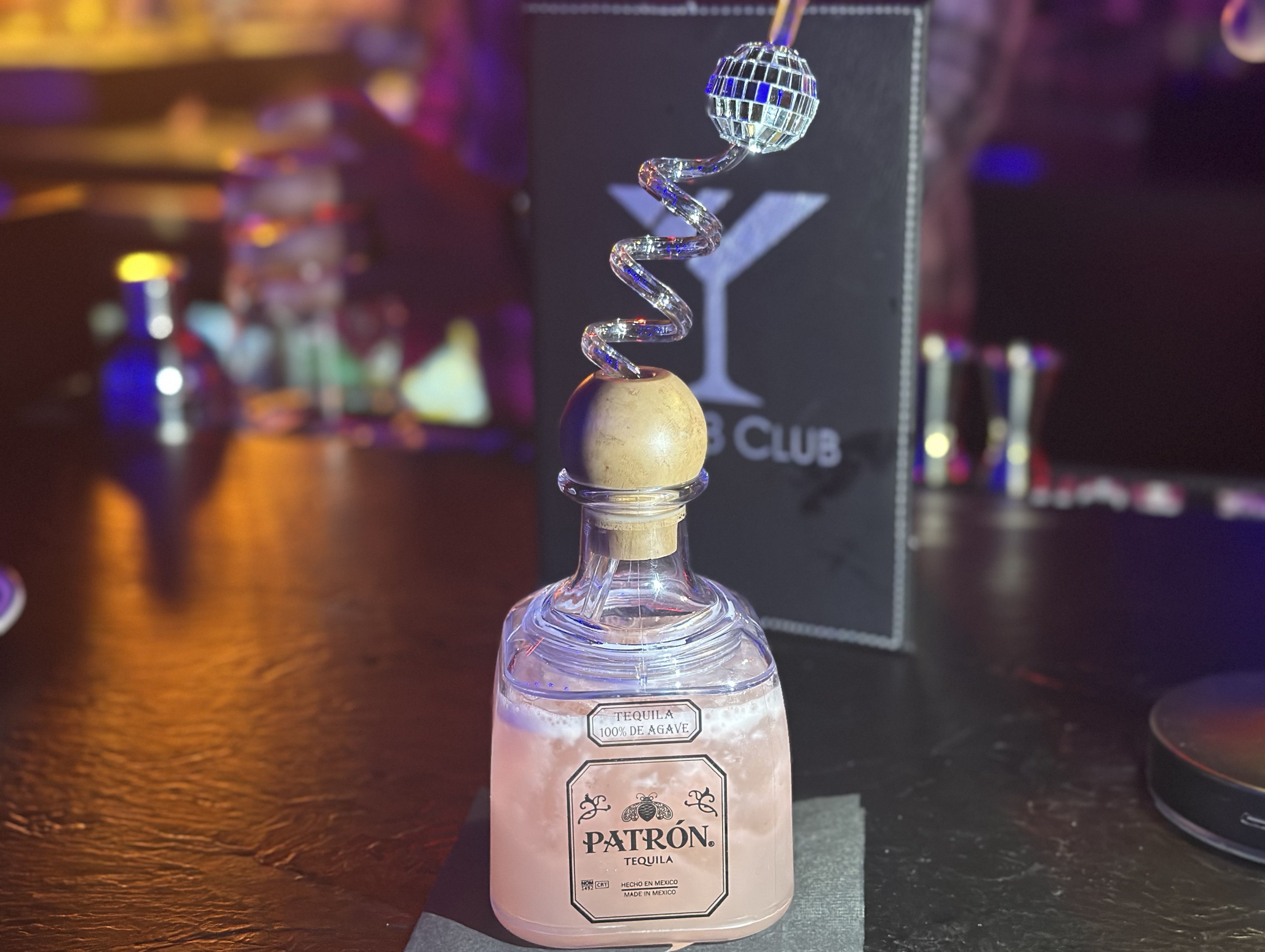 A pink margarita in a mini Patron bottle with a curly straw that has a disco ball on top at The 88 Club.