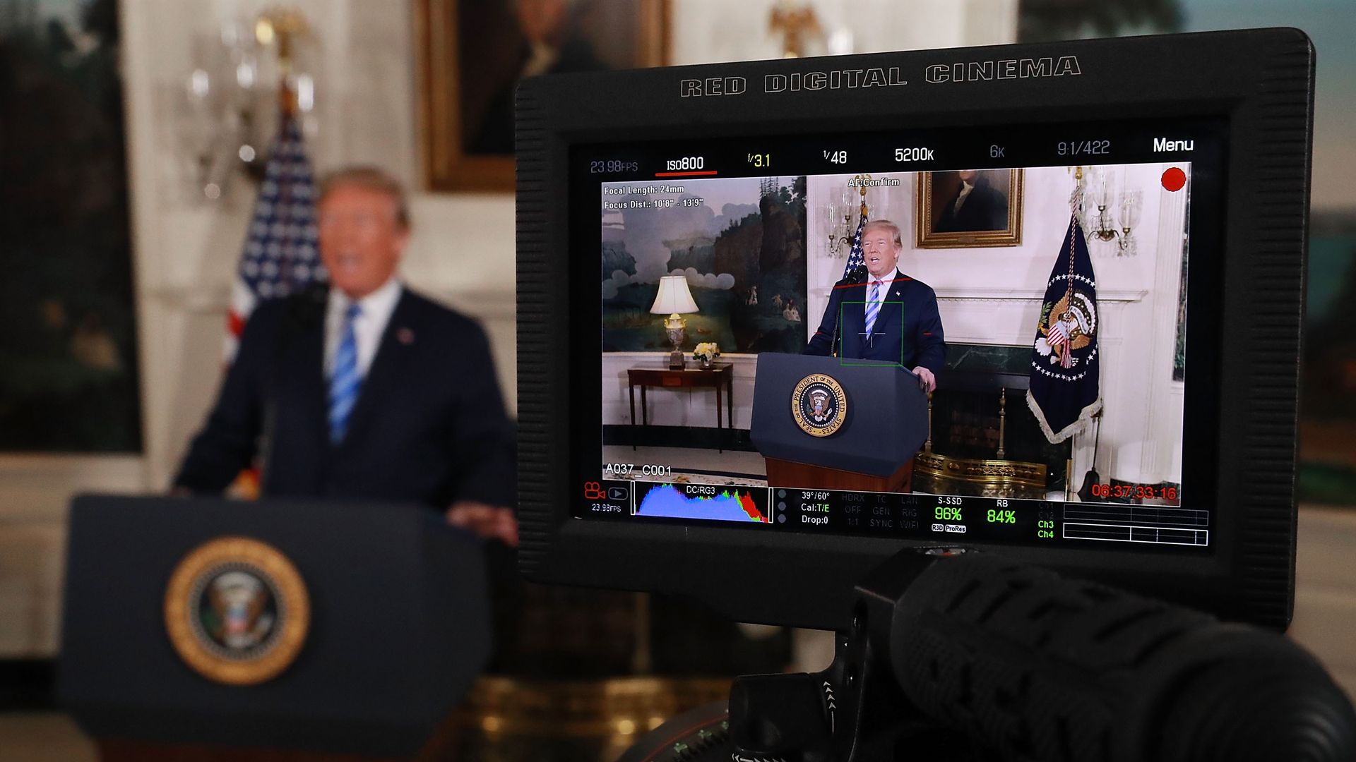 President Trump at podium next to video image of himself