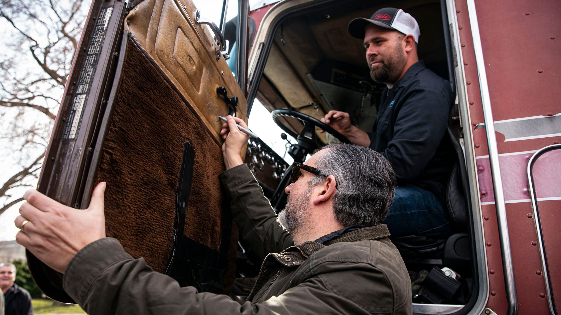 Sen. Ted Cruz is seen autographing the door of a truck participating in a truckers' protest against vaccine mandates.
