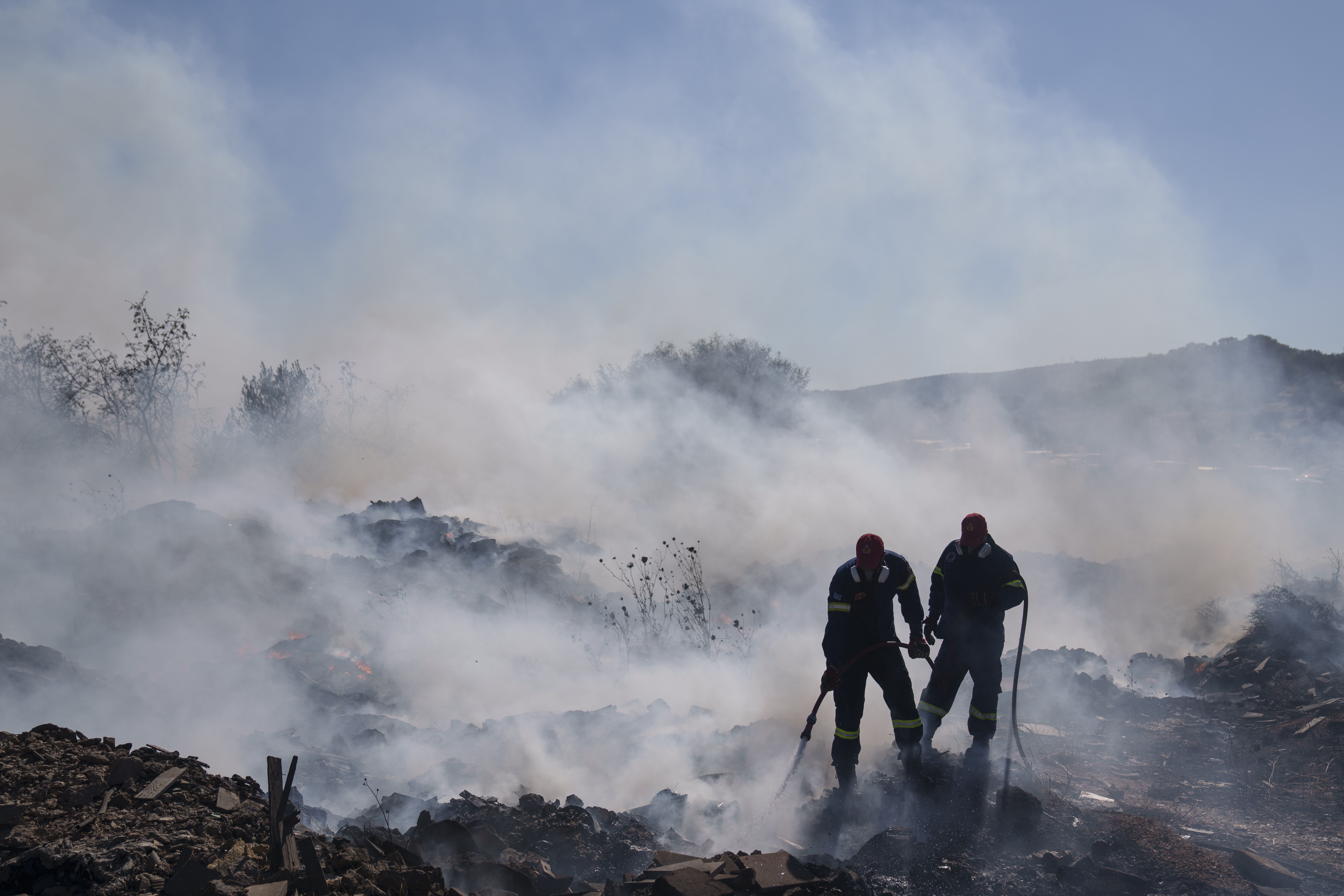 Firefighters try to extinguish the fire burning in Koropi suburb, eastern part of Athens, Wednesday, June 19, 2024. Scores of Greek firefighters and water-bombing aircraft were trying to contain a large wildfire on the fringes of Athens that forced authorities to issue evacuation orders Wednesday fo