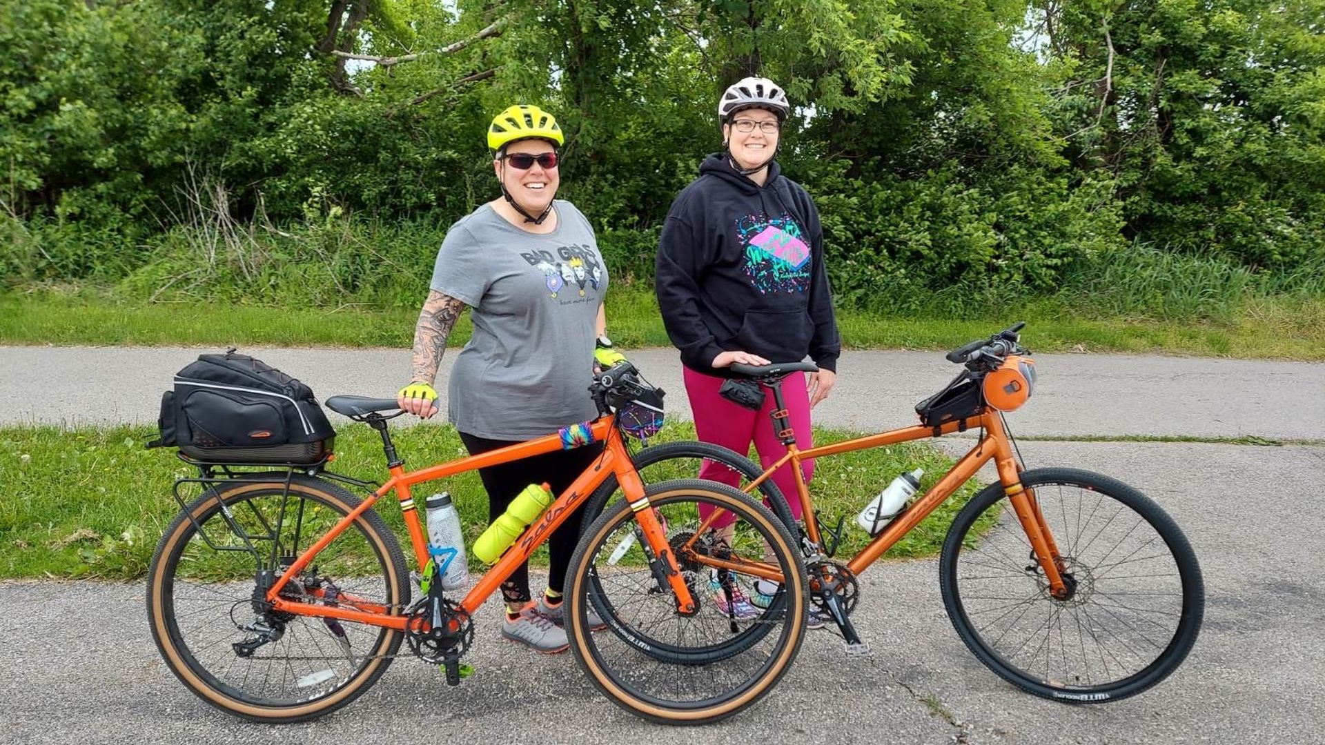 Two ladies standing next to their orange bikes