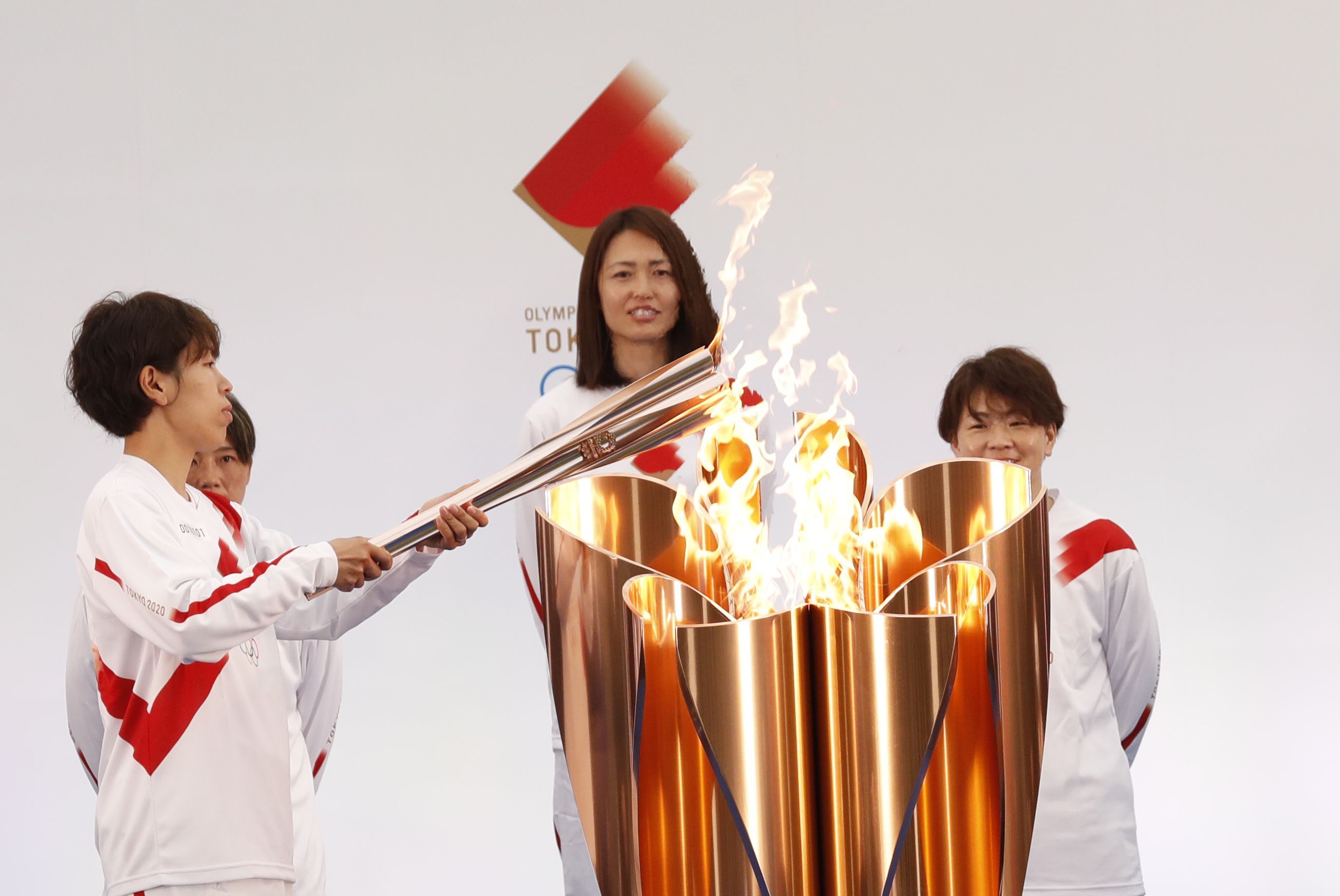  Azusa Iwashimizu (L), member of Japan women's football national team, lights the torch from the celebration cauldron during the Tokyo 2020 Olympic Torch Relay Grand Start at the J Village on March 25