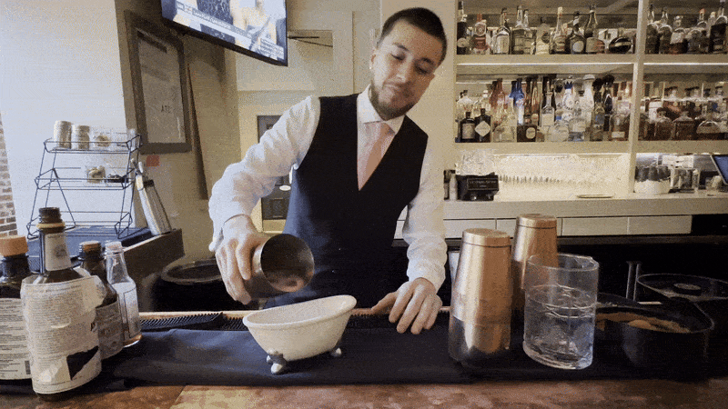 Image shows a bartender pouring a drink into a tiny bathtub.