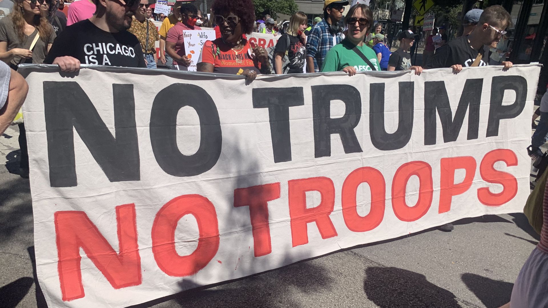 People hold a sign on the street that says "No Trump No Troops" 