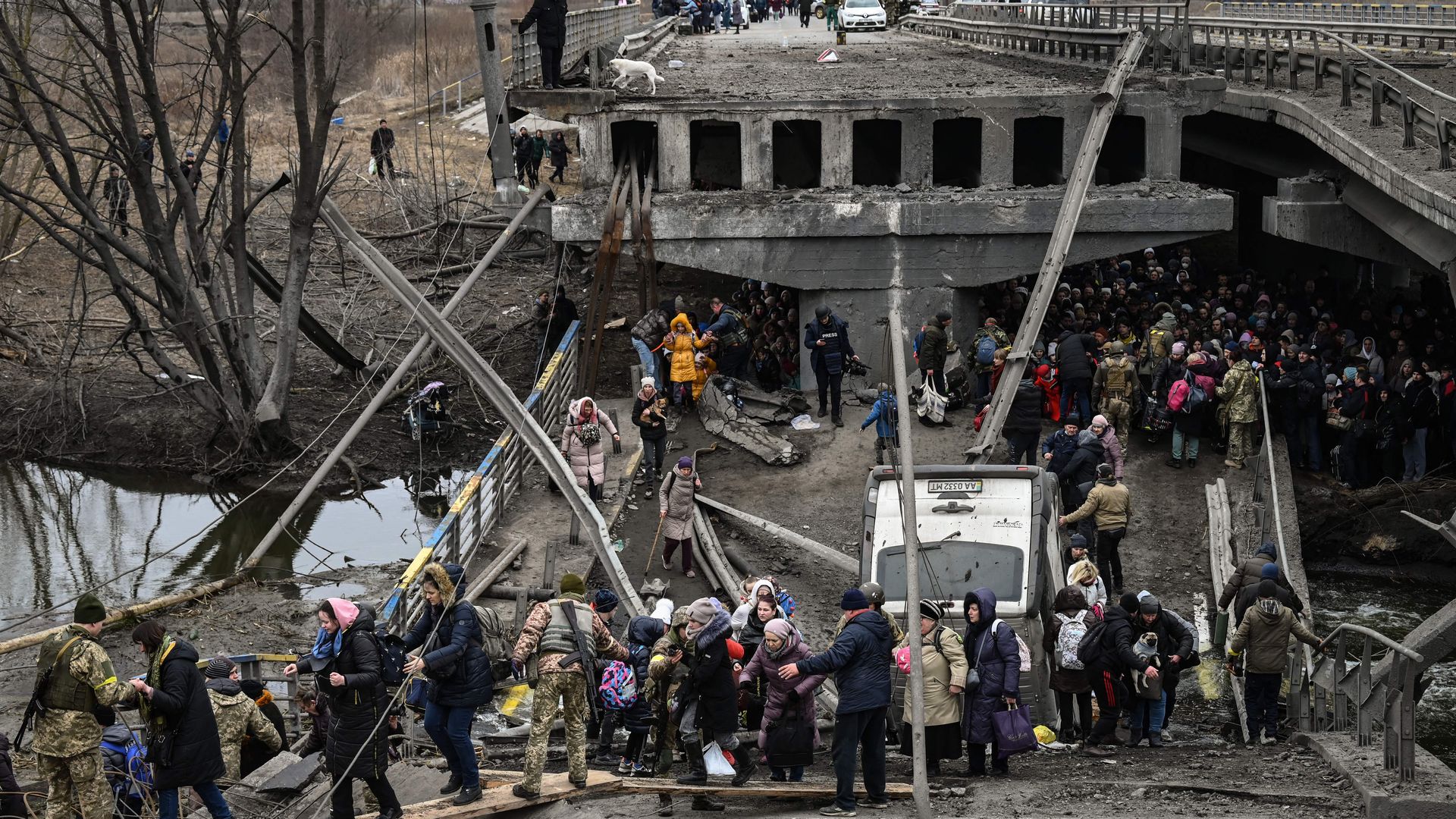 People cross a destroyed bridge as they evacuate the city of Irpin, northwest of Kyiv, during heavy shelling and bombing on March 5, 2022,