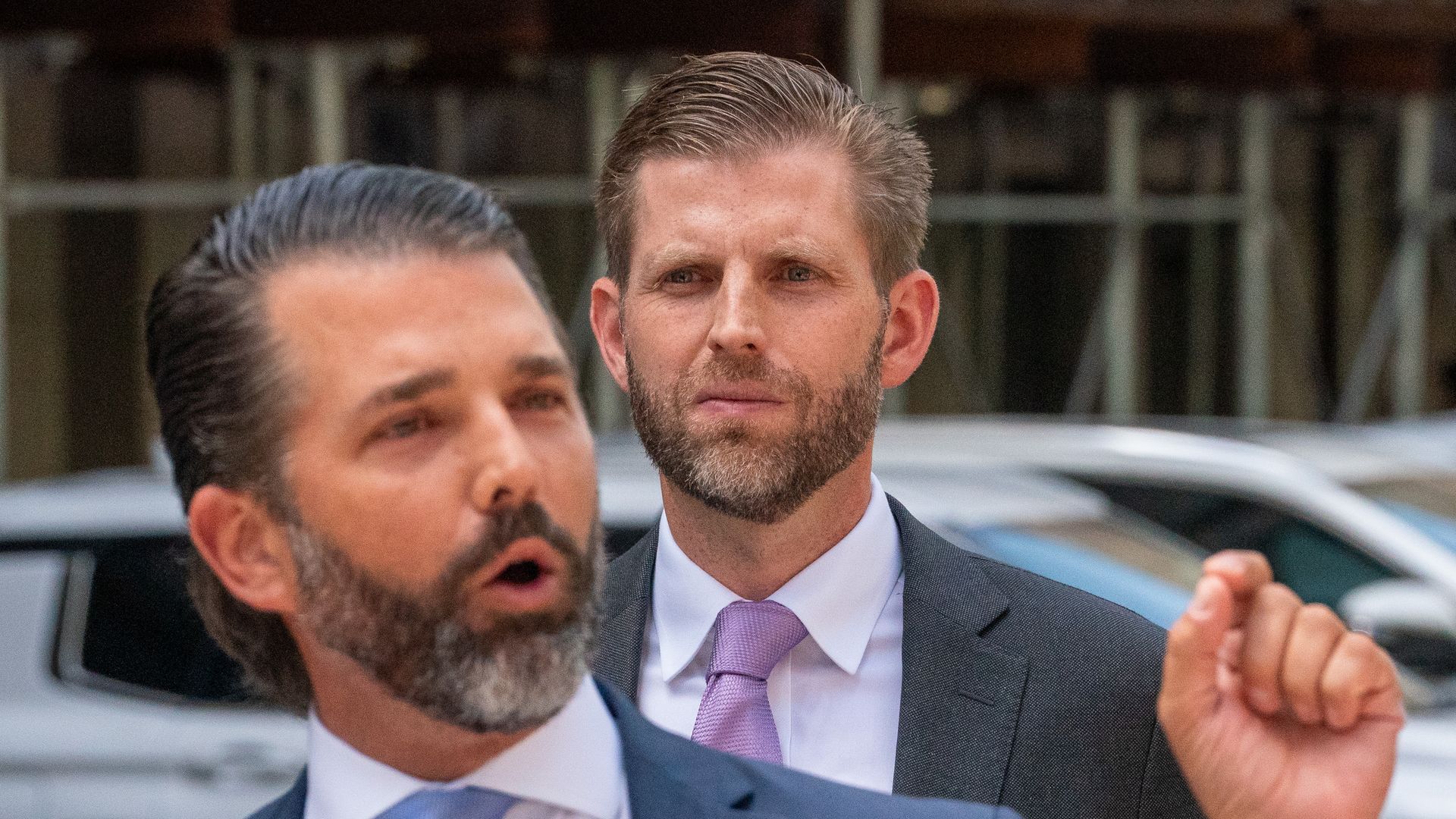 Two men in grey suits. One in the foreground, one in the background.