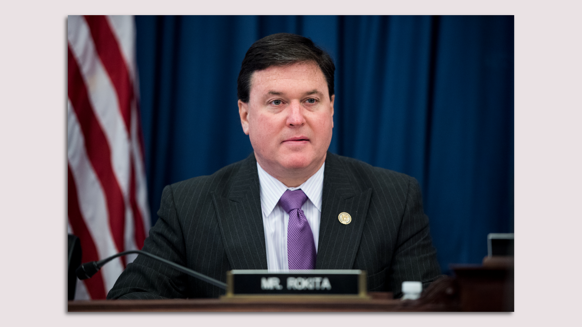 A man in a suit sits at a desk 