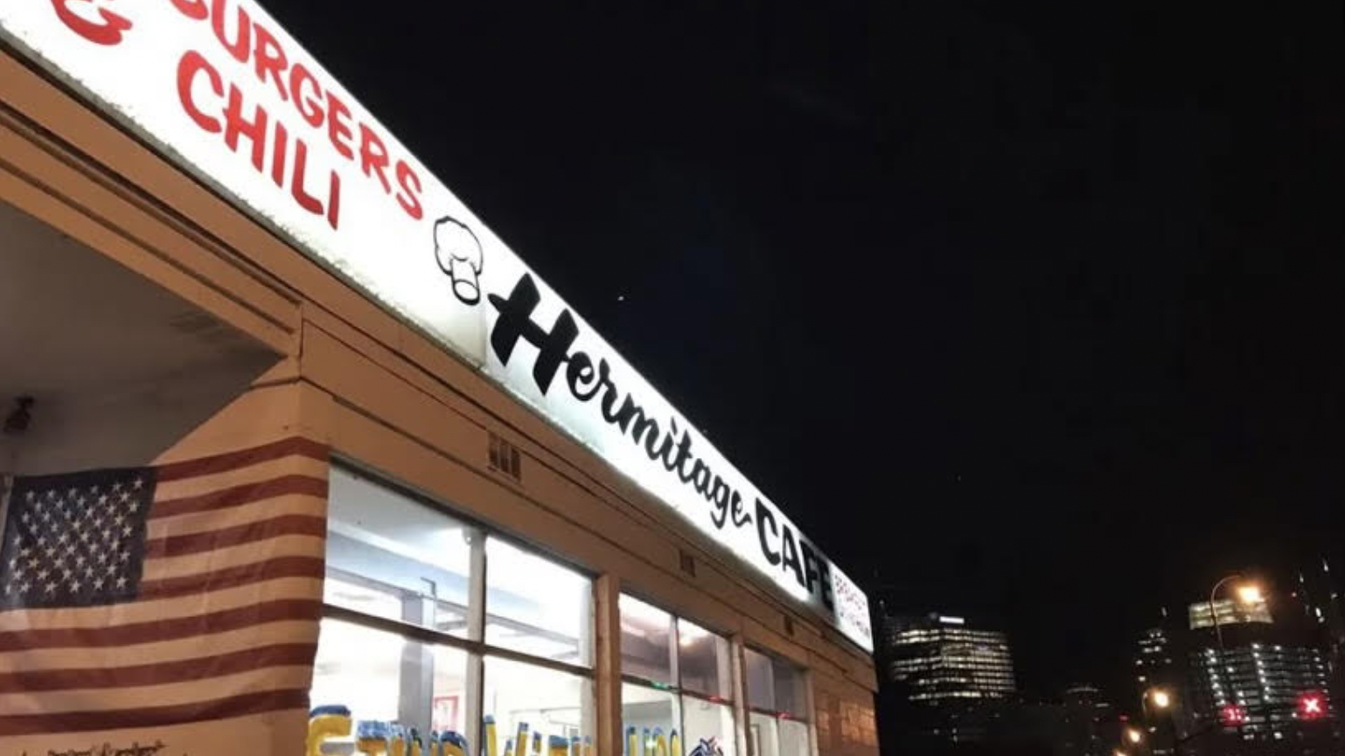 Hermitage Cafe's bright sign lit up at night.