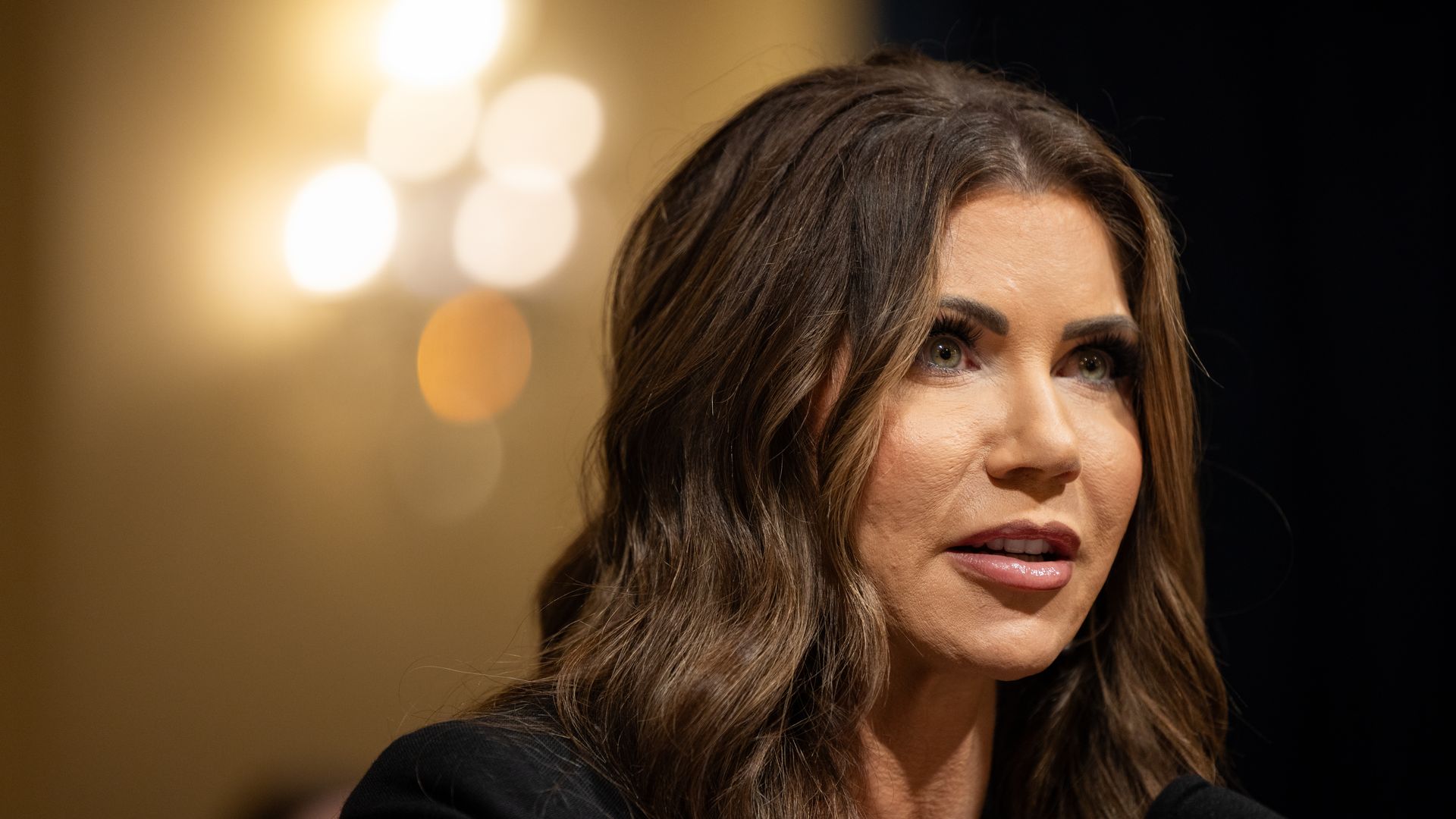 Homeland Security Secretary Kristi Noem photographed speaking into a microphone 